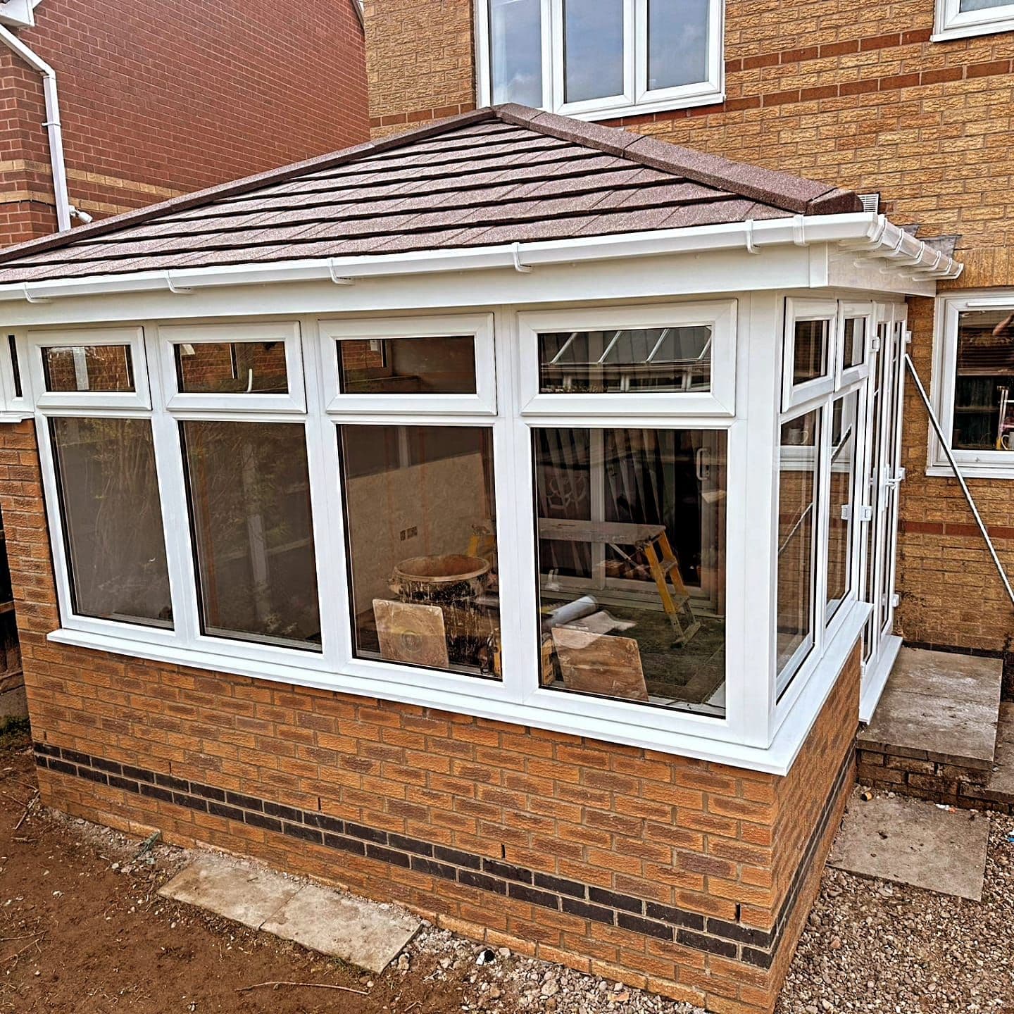 Conservatory with a new brown tiled warm roof and white frames