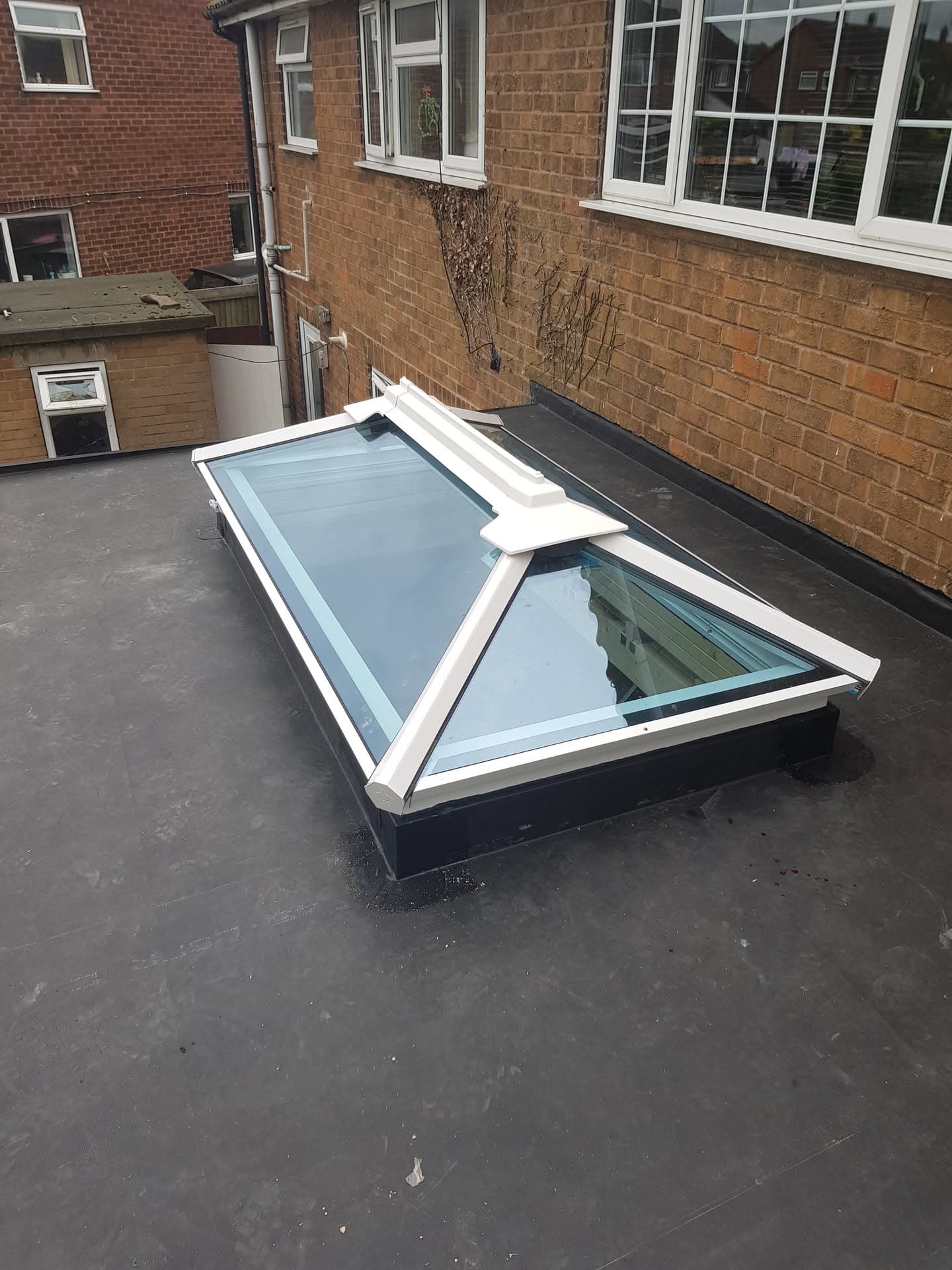 Flat roof with white-framed roof lantern installed on dark grey felt surface