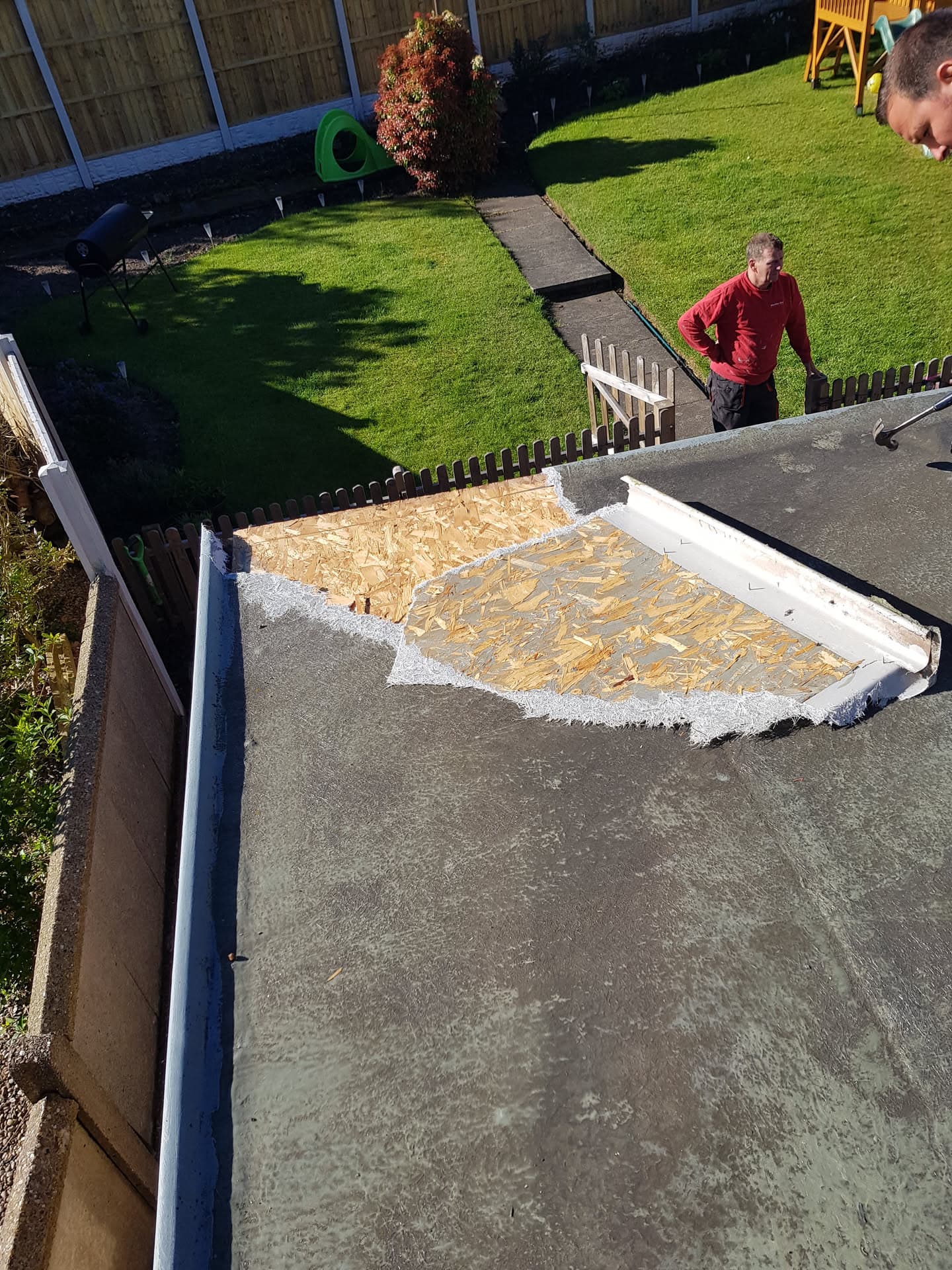 Flat roof repair in progress showing exposed OSB decking and white fascia trim