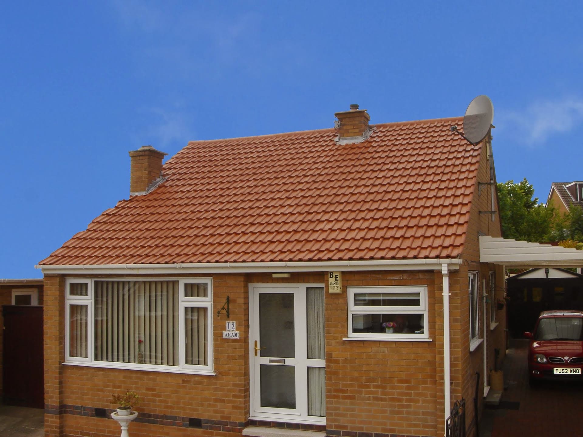 Pitched roof with red clay tiles and two brick chimney stacks