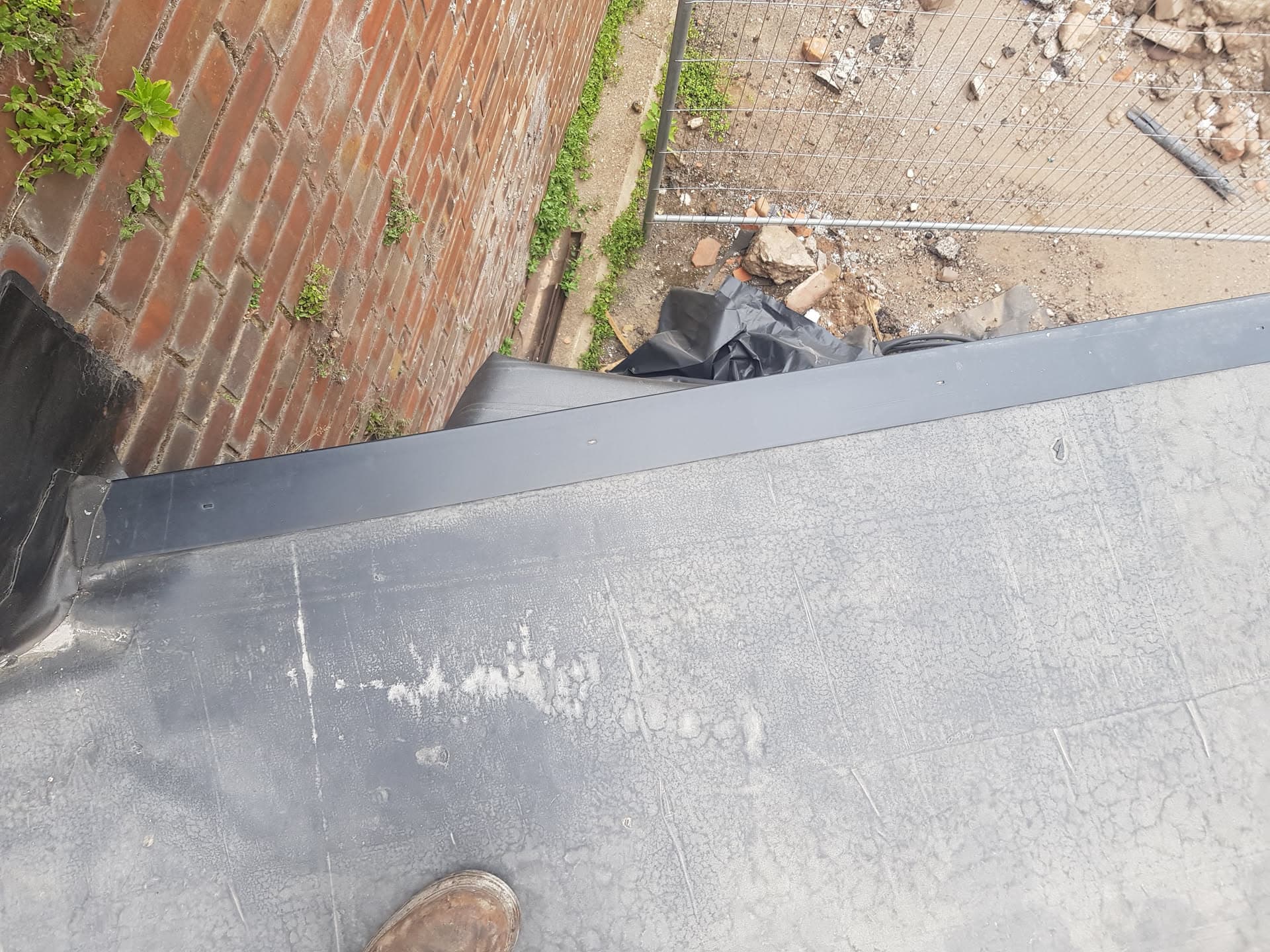 Grey flat roof with lead flashing detail and adjacent tiled roof