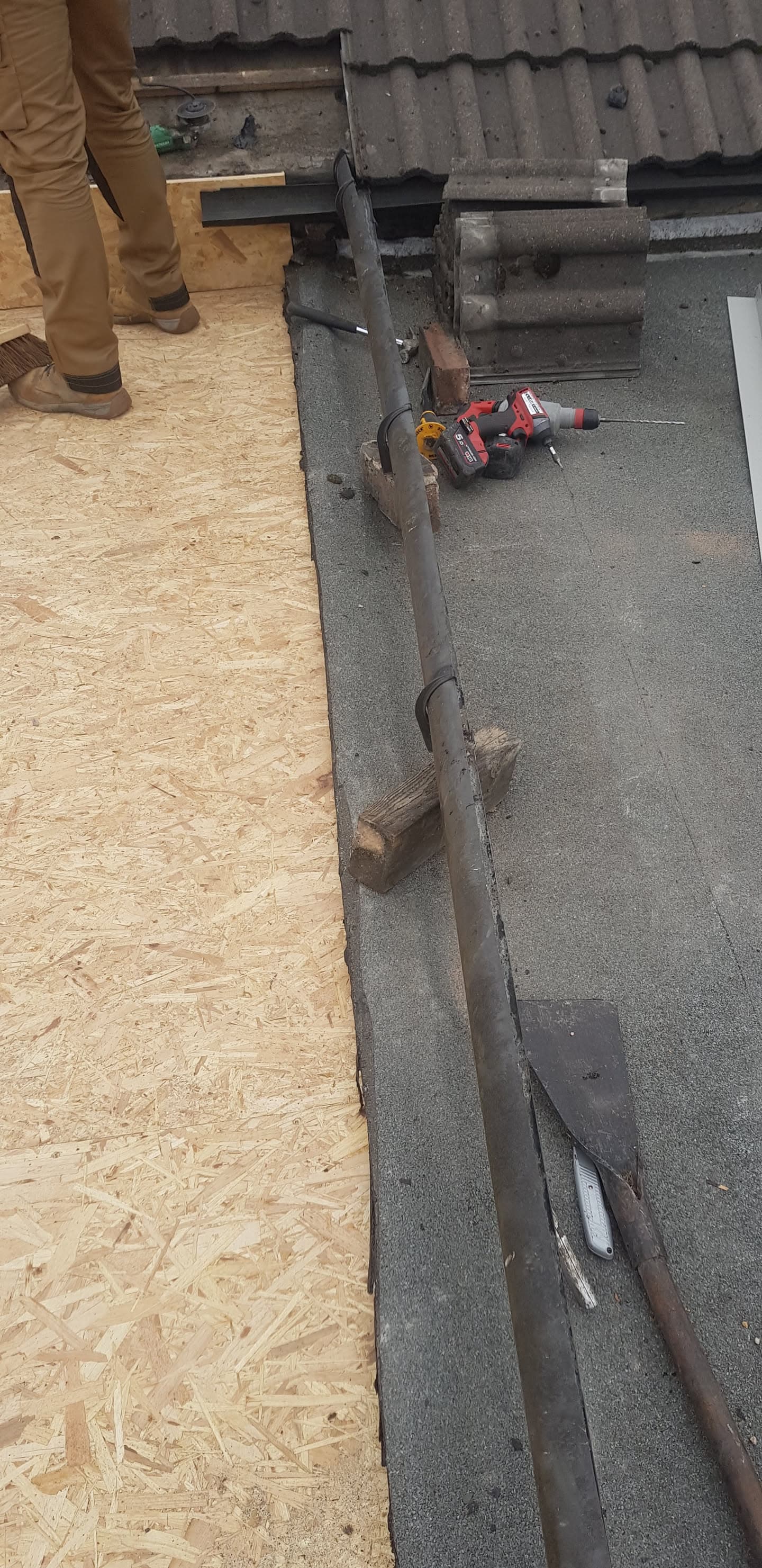 Flat roof installation with felt covering and fascia board, fitter visible on OSB decking