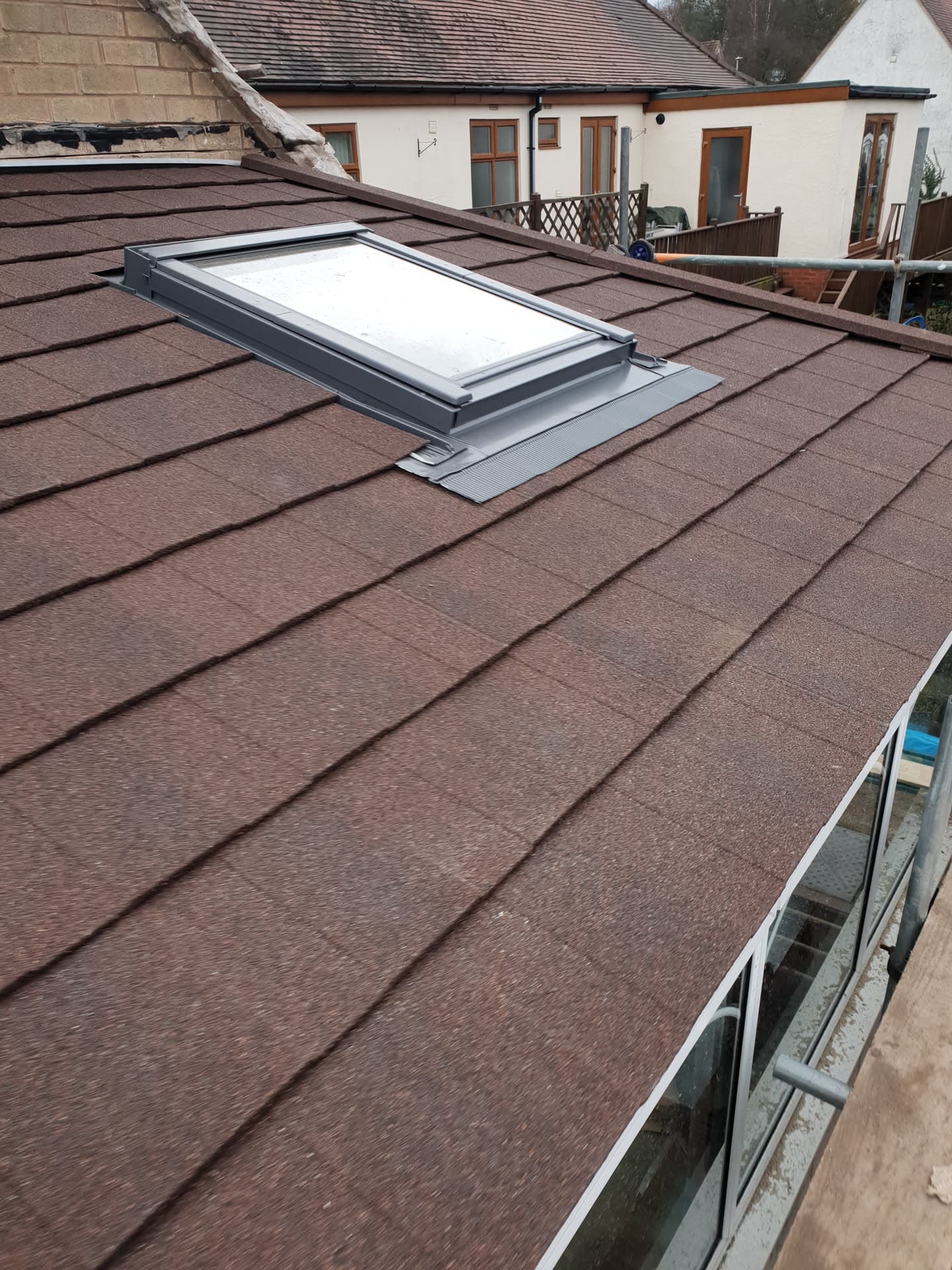 Brown tiled pitched roof with newly installed roof window and lead flashing