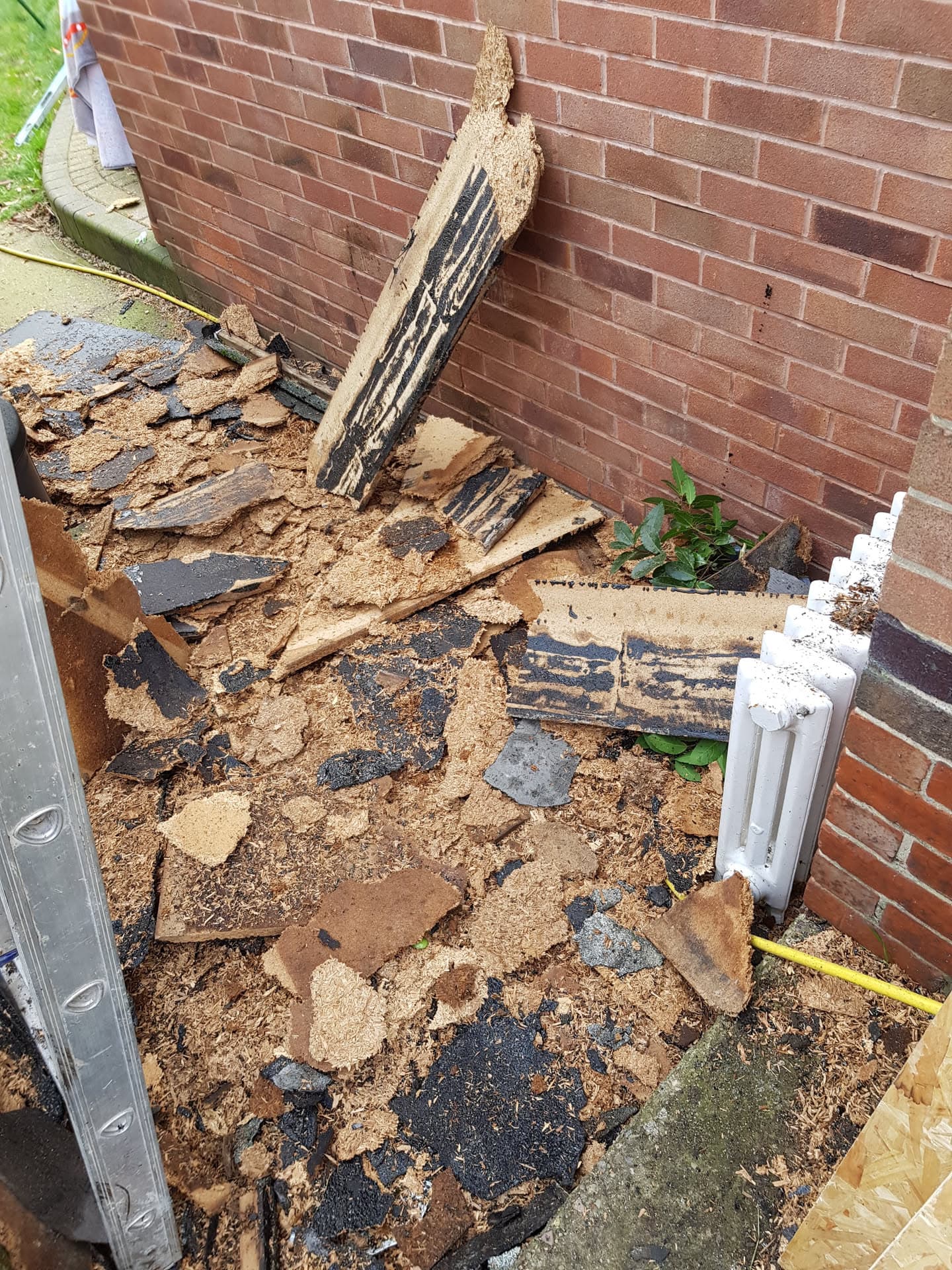 Removed deteriorated flat roof felt and decking showing damaged substrate before replacement