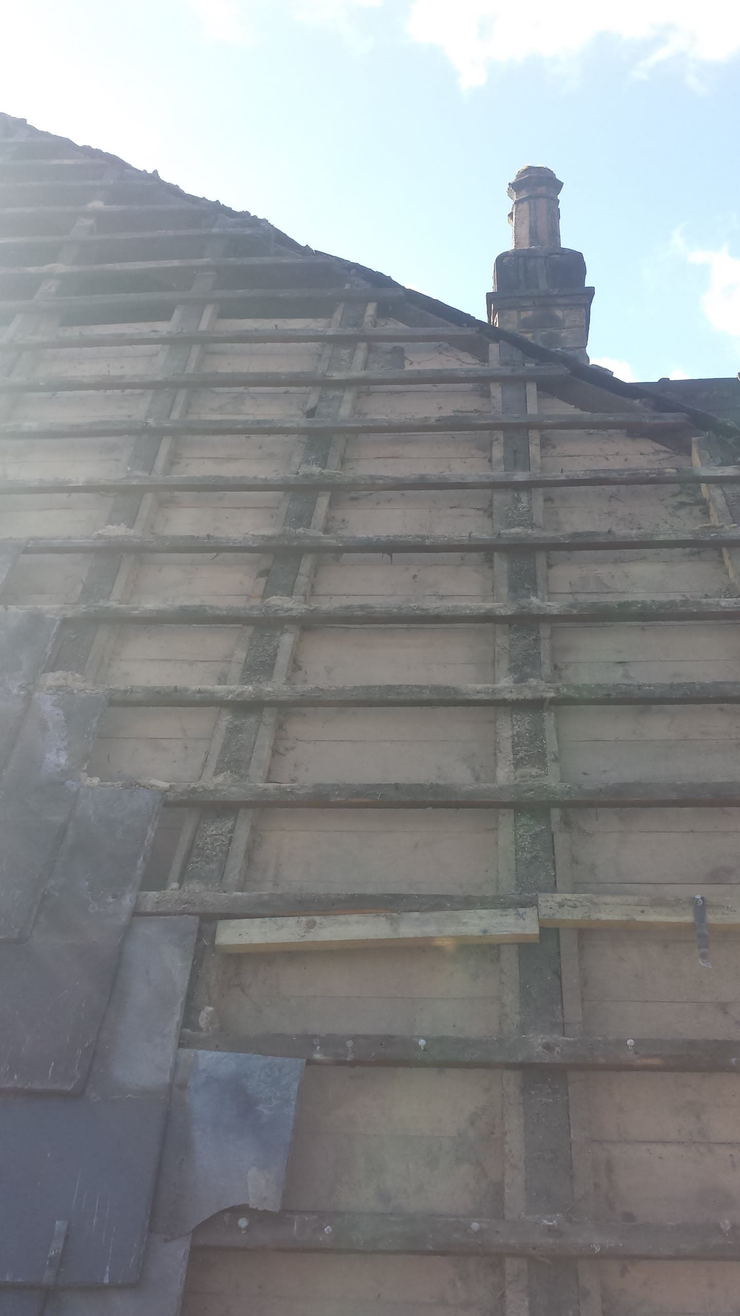 Pitched roof with exposed timber battens and chimney stack during re-roofing work