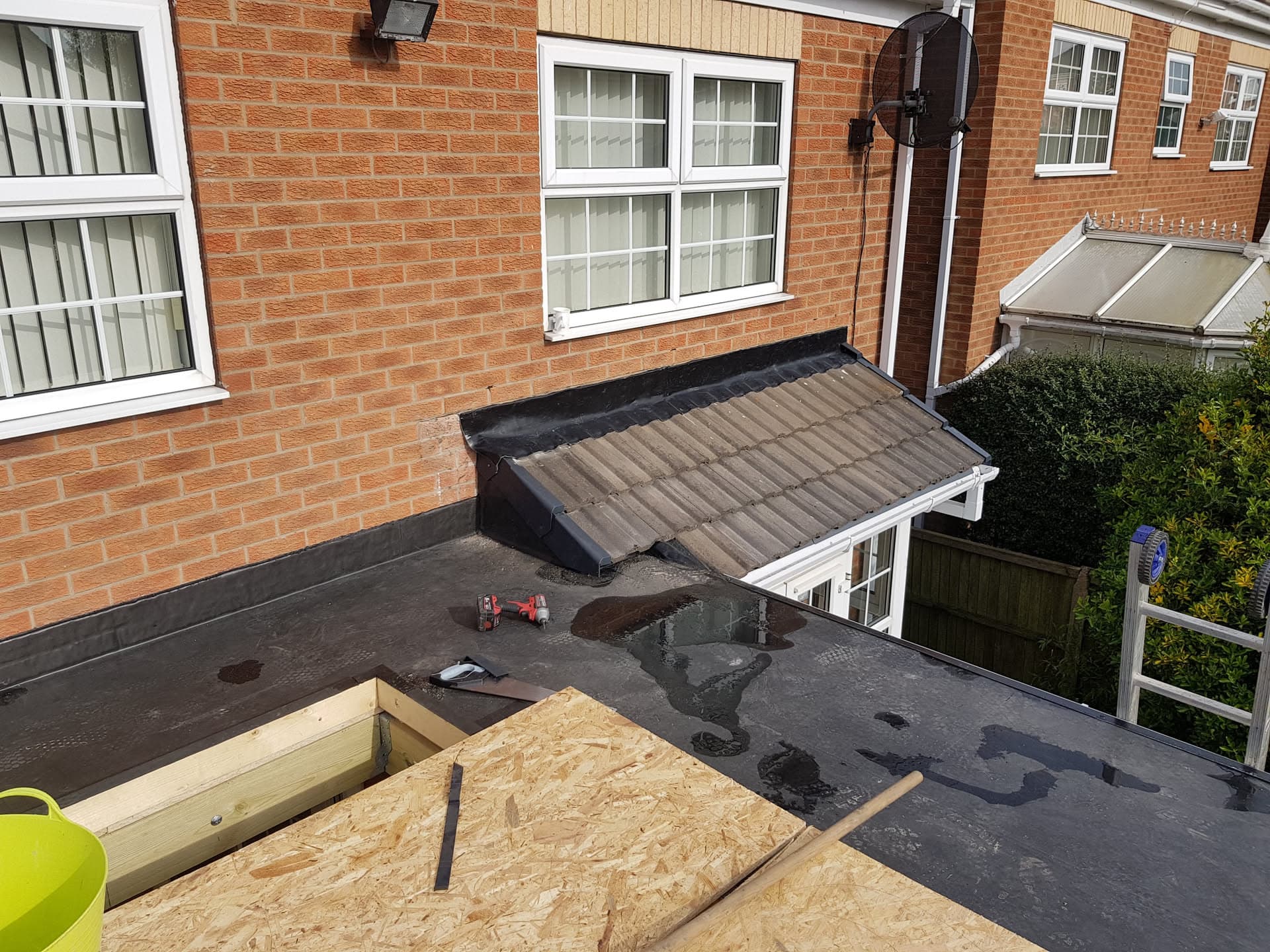 Flat roof installation in progress with felt covering and timber framework visible
