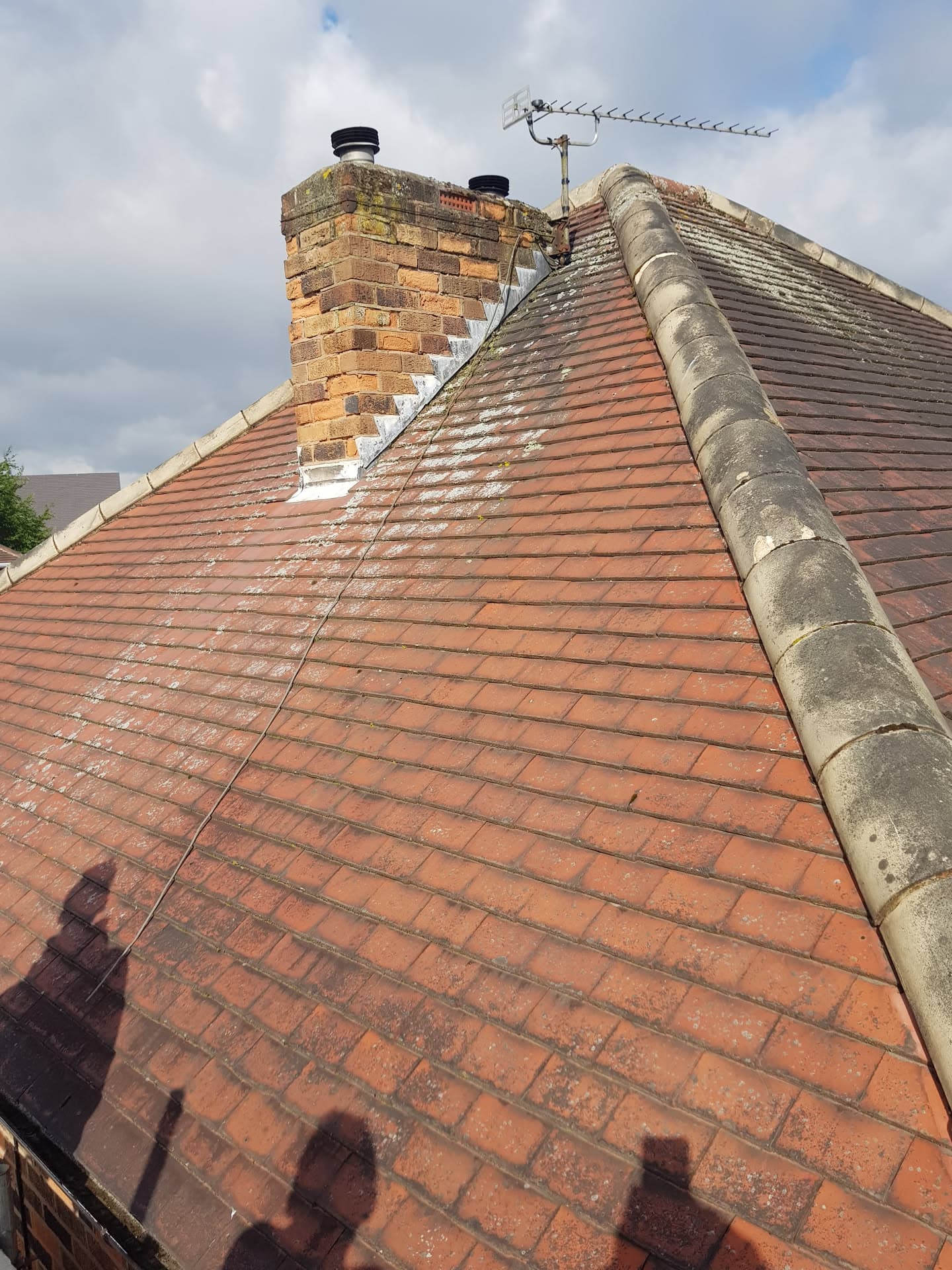 Pitched roof with terracotta concrete tiles, brick chimney stack and ridge tiles