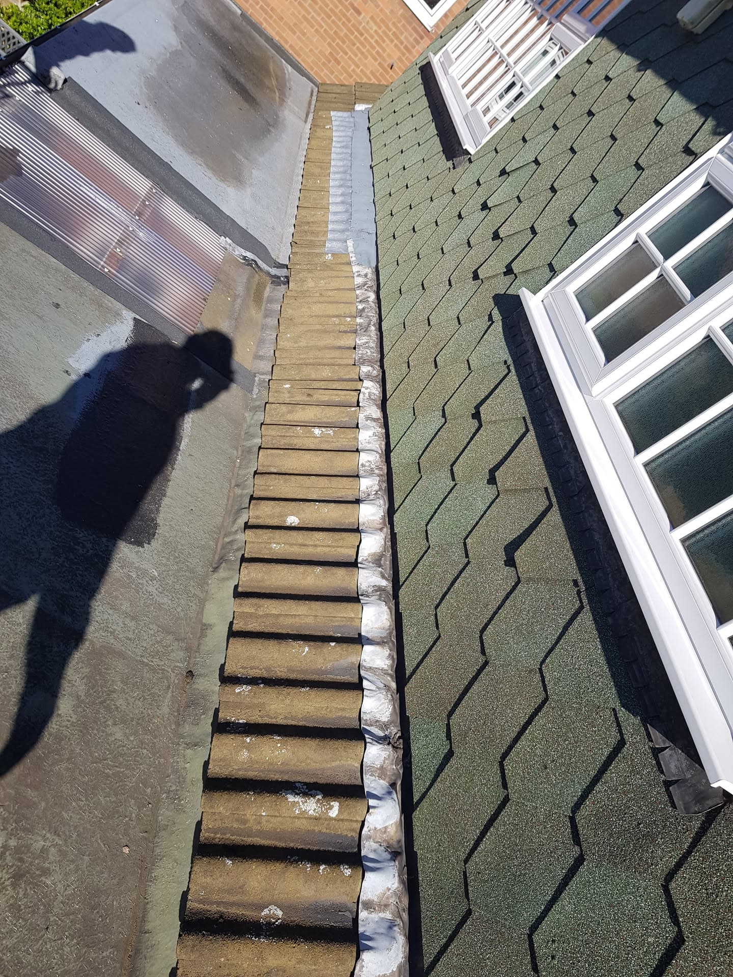 Aerial view of flat roof with green mineral felt and brown ridge tiles with lead flashing