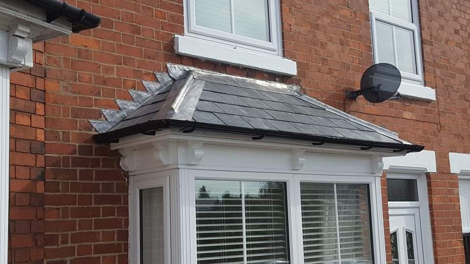 Slate bay window roof with decorative lead ridge detail on brick house