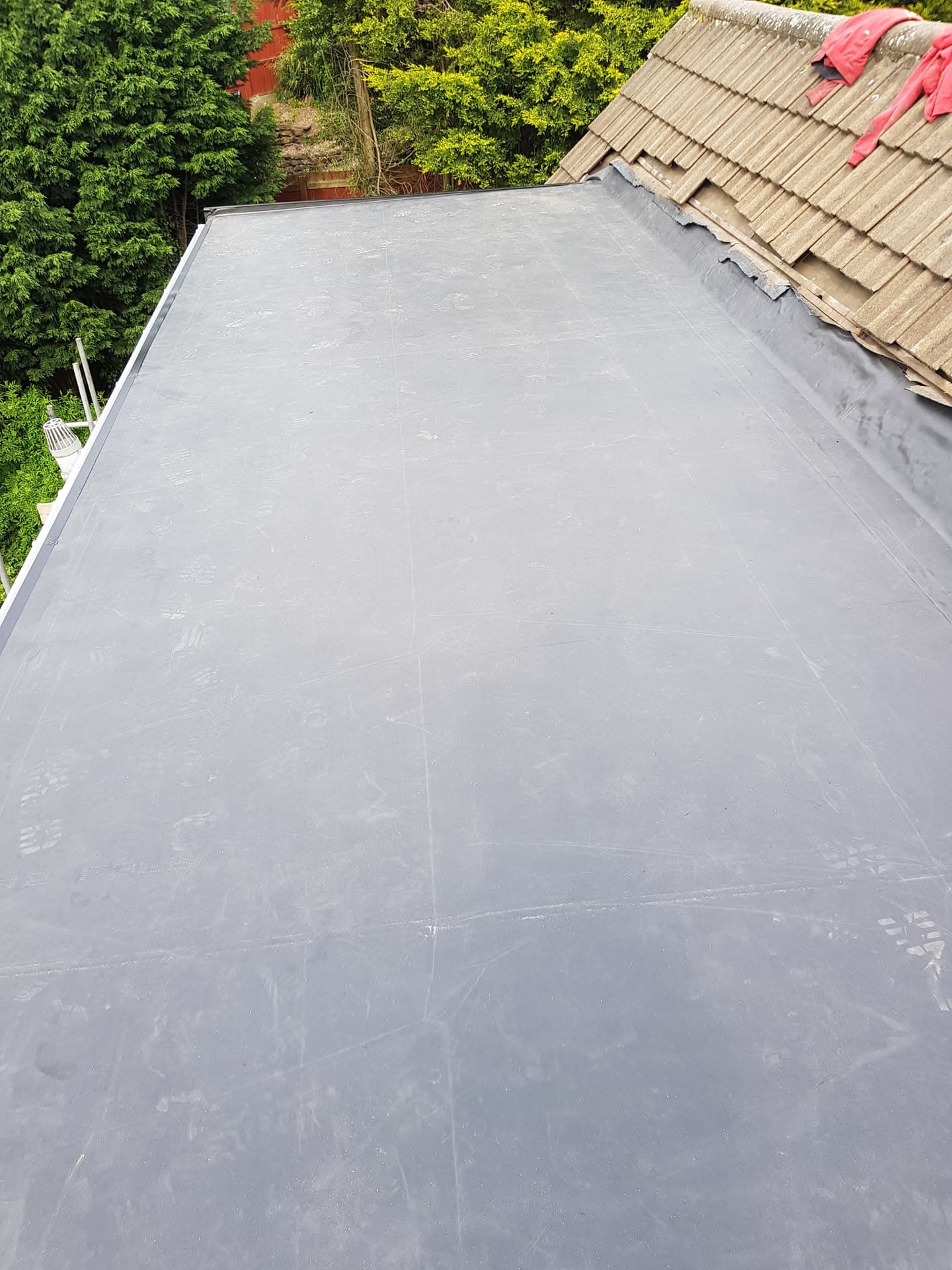 Grey flat roof with EPDM rubber membrane alongside pitched roof with concrete tiles