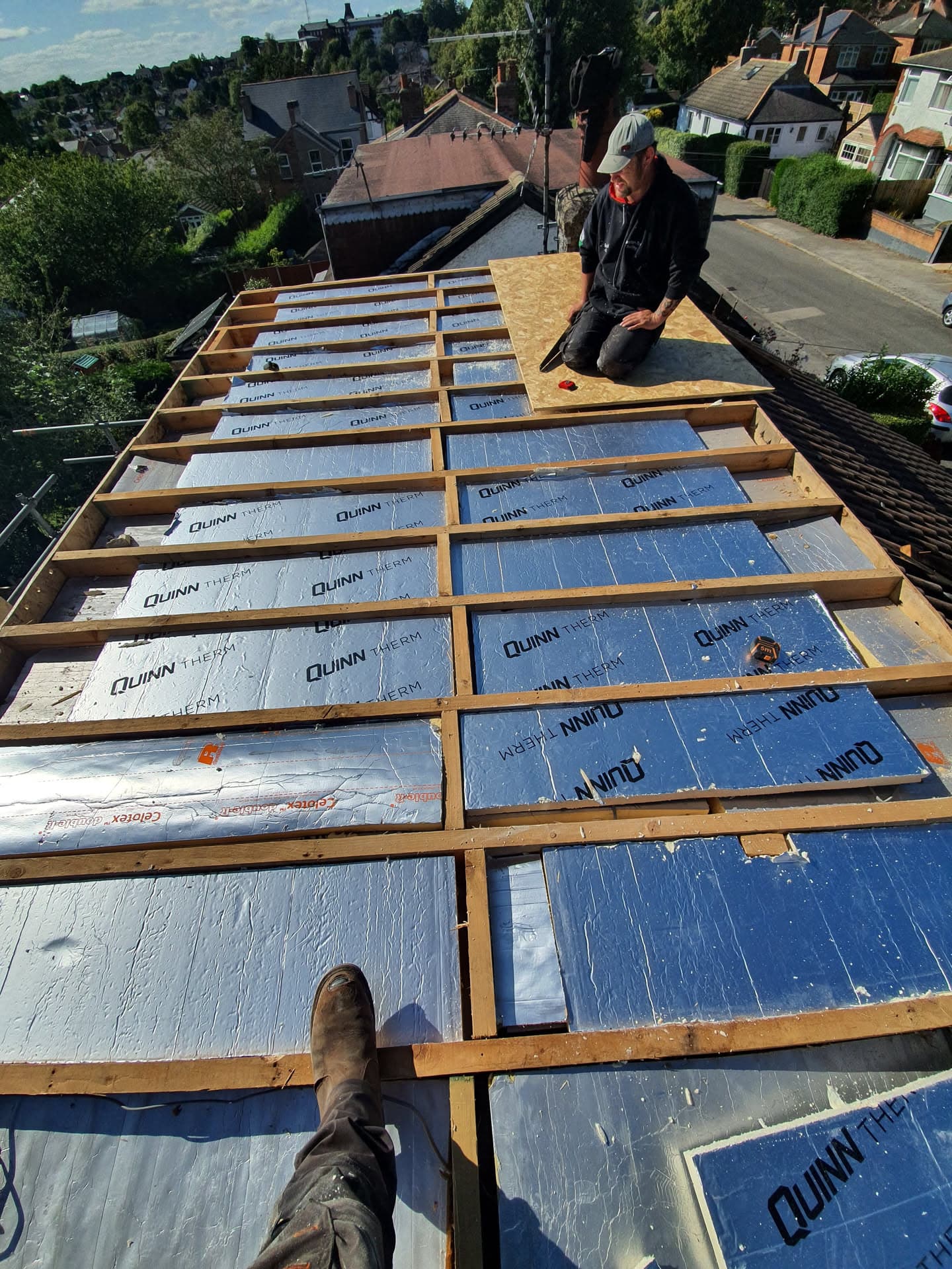 Fitter working on pitched roof with timber battens and blue breathable membrane installed