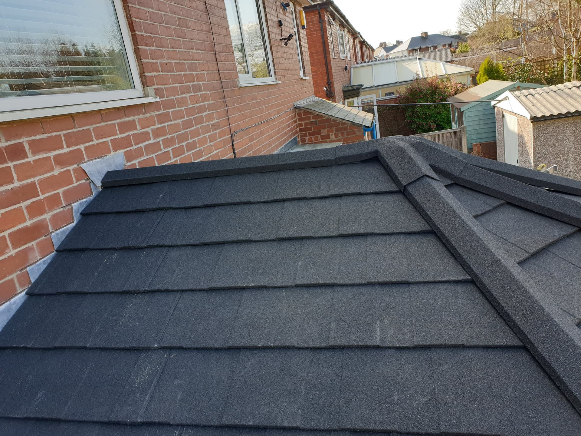 Newly installed flat roof with dark grey felt covering on residential extension