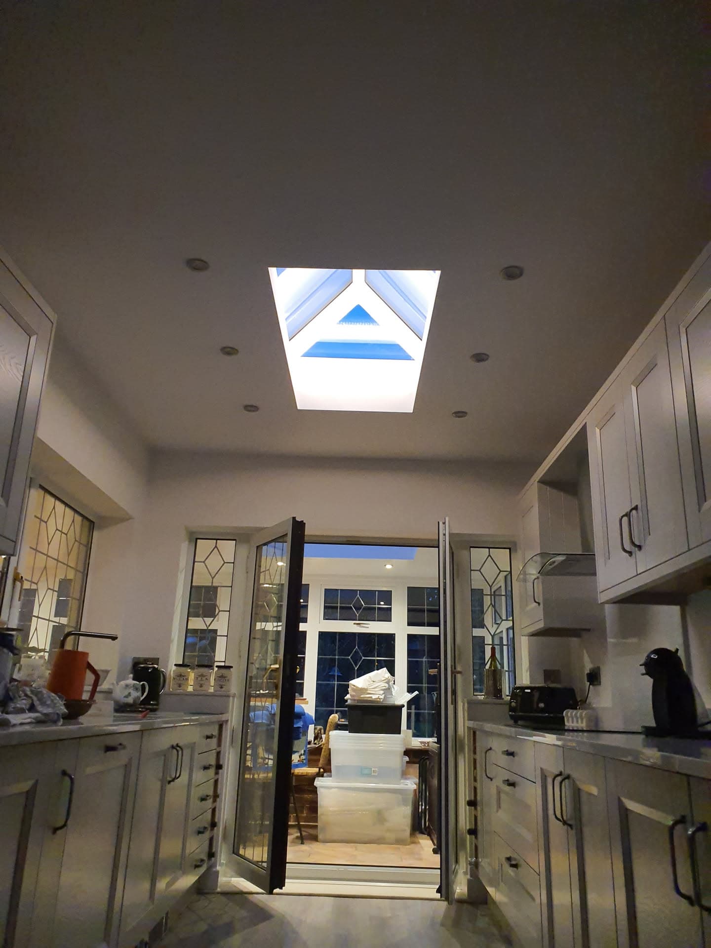 Flat roof lantern skylight installed in kitchen ceiling with white frame and blue sky visible