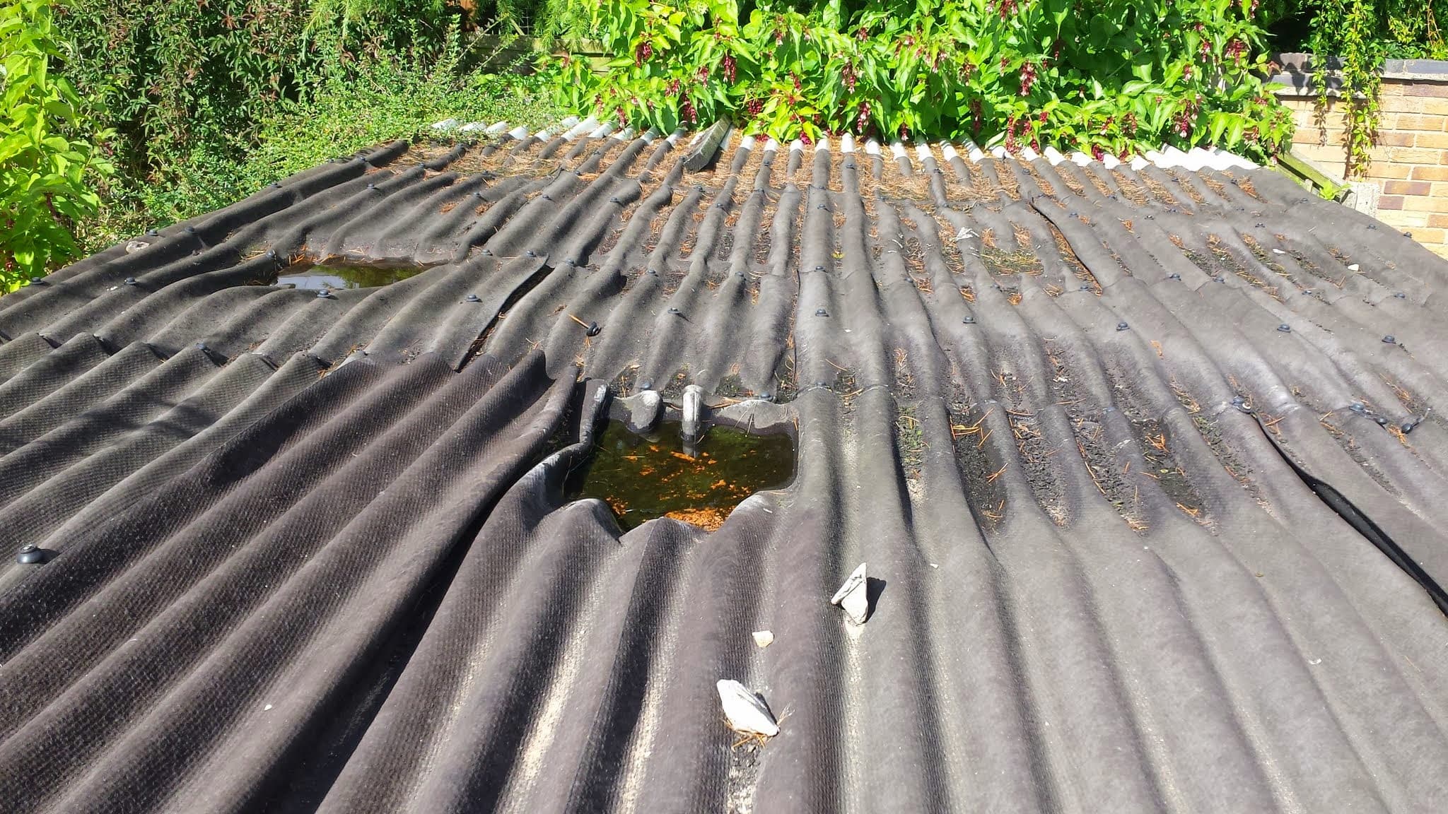 Weathered corrugated metal roof with moss growth and visible damage