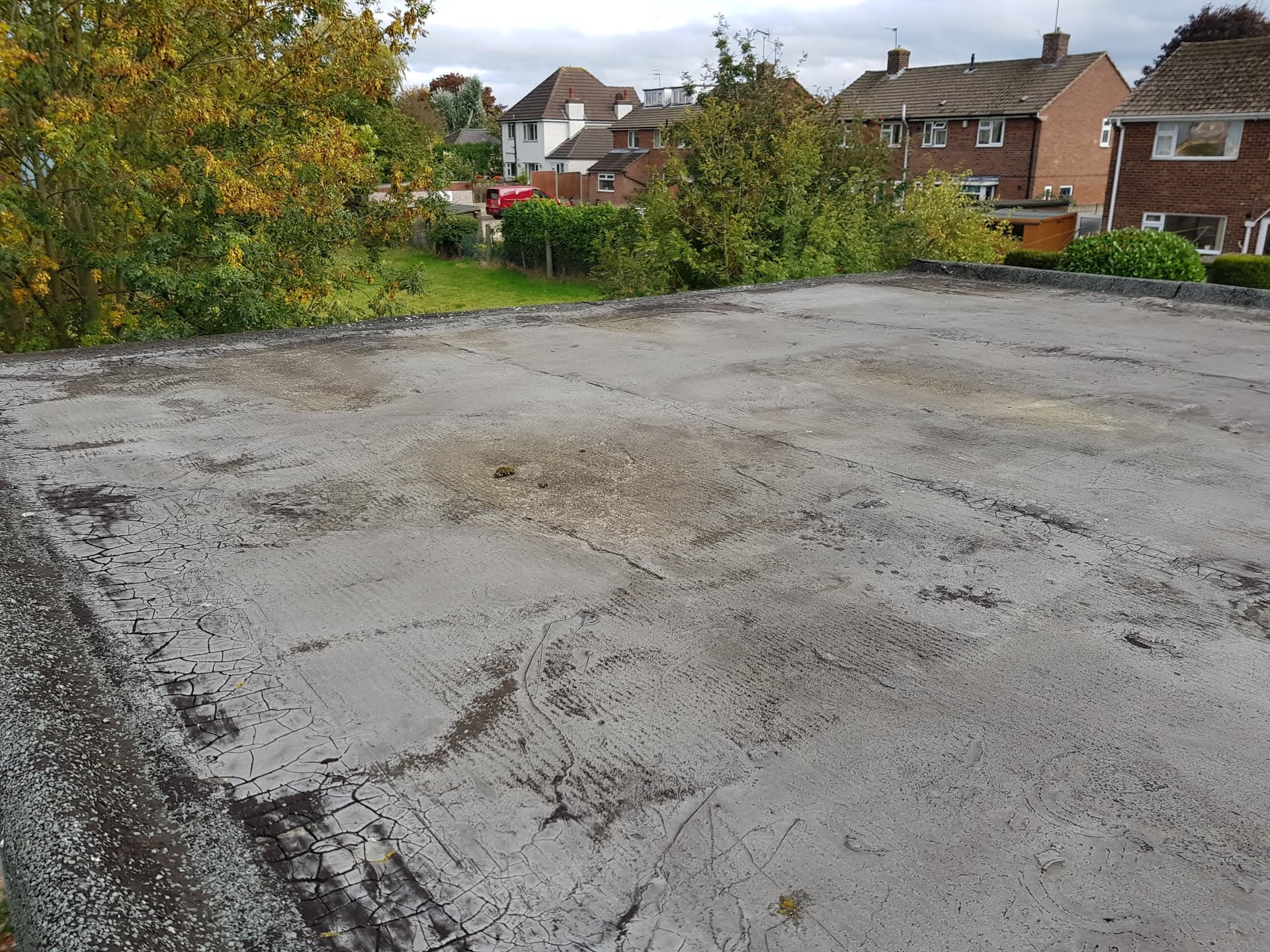 Large flat roof with grey felt surface on residential building
