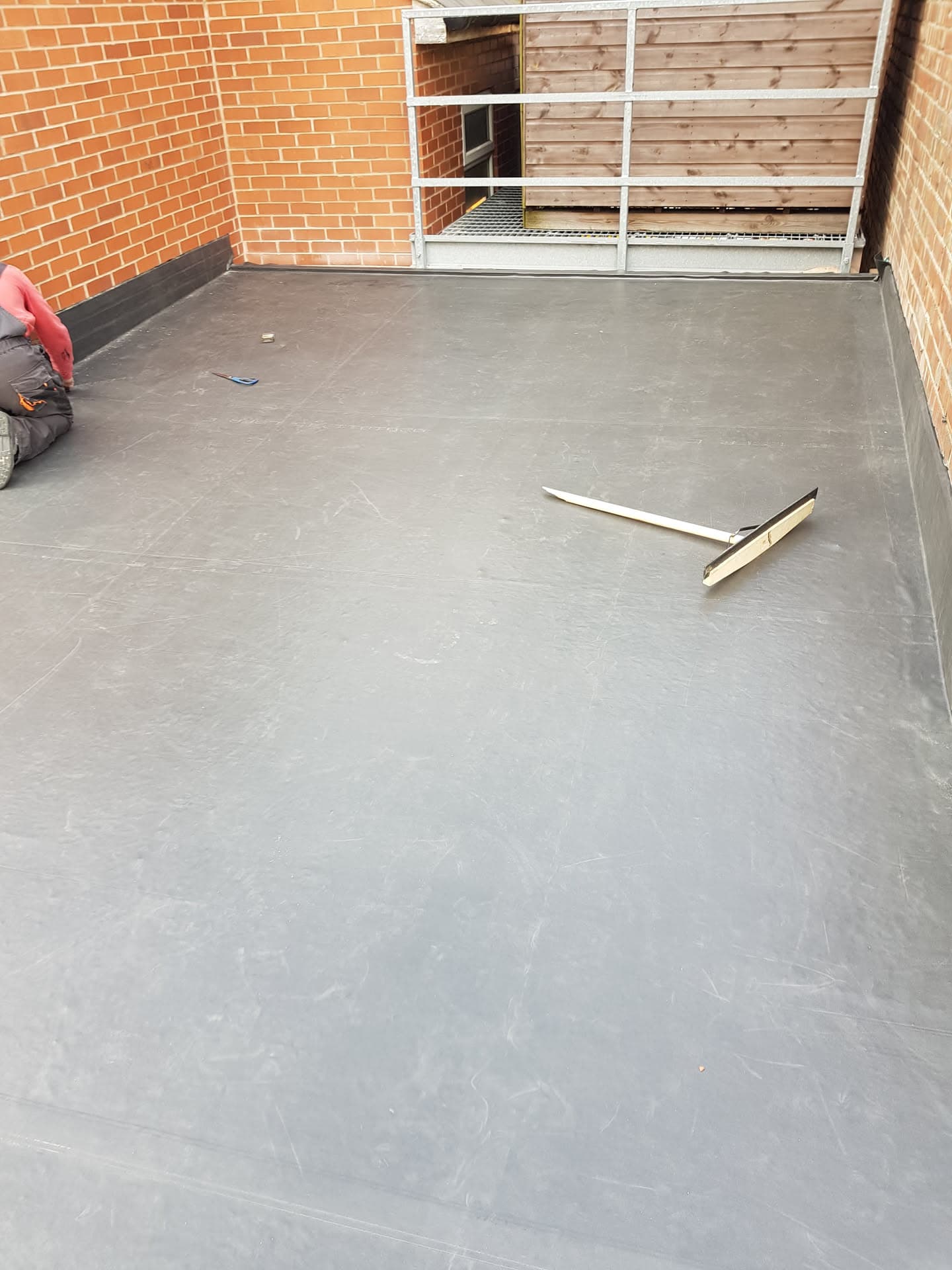Grey GRP fibreglass flat roof installation with smoothing tool