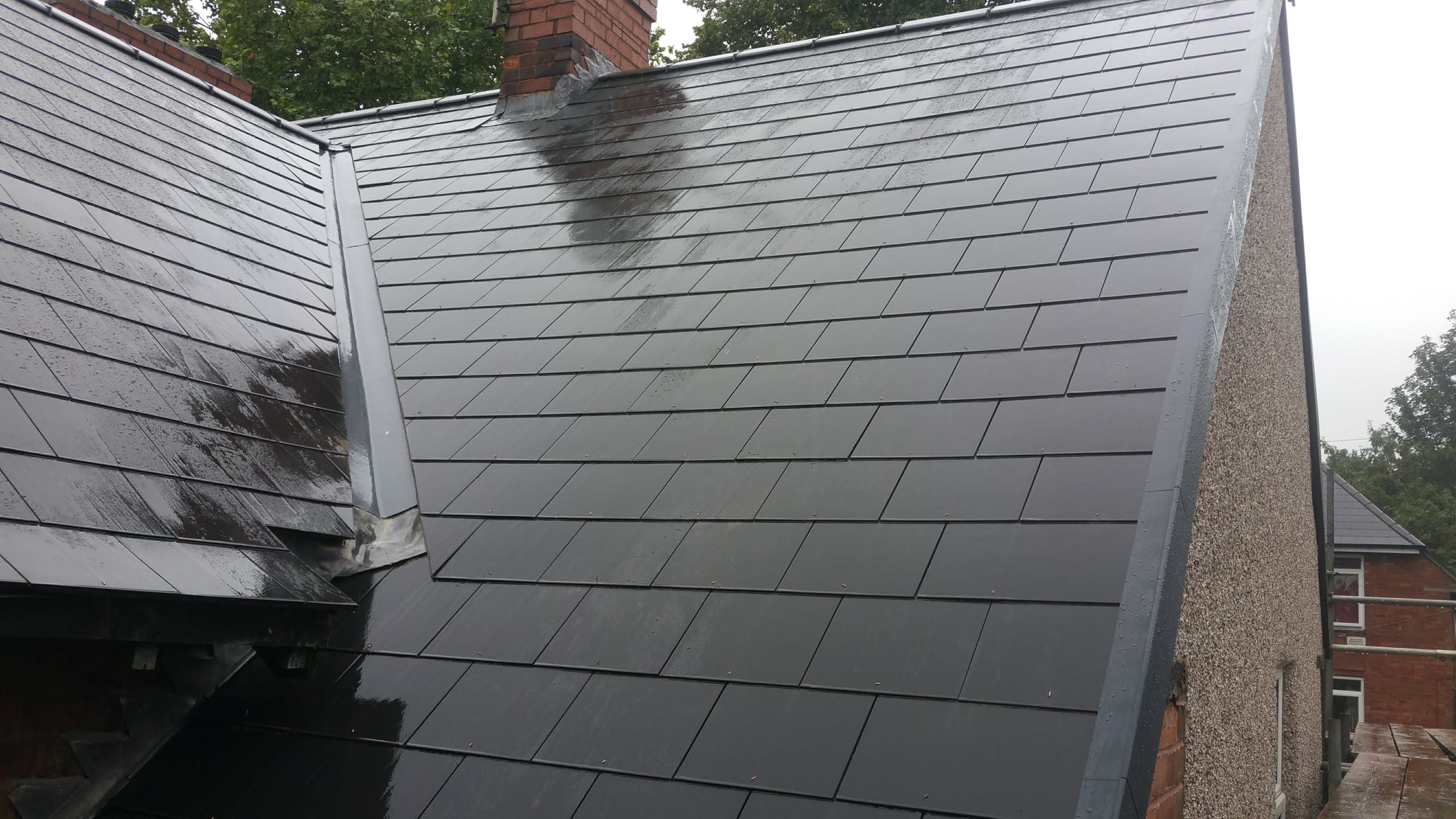 Grey slate pitched roof with white fascia and brick chimney stack