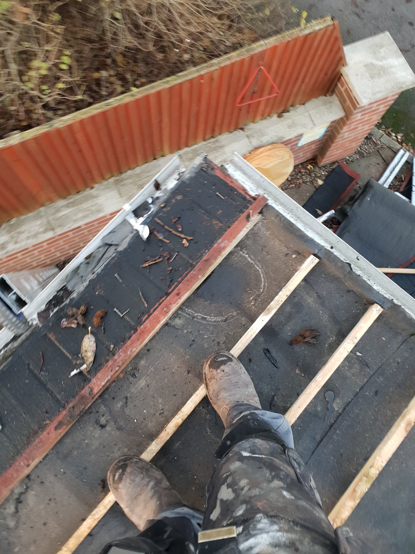 Fitter standing on flat roof with felt and timber battens, overlooking neighbouring tiled roofs