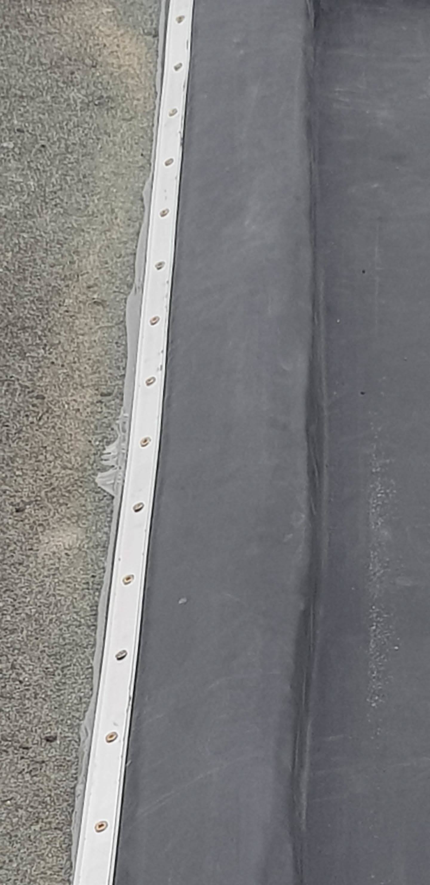 Flat roof edge detail showing grey EPDM rubber membrane with white drip trim