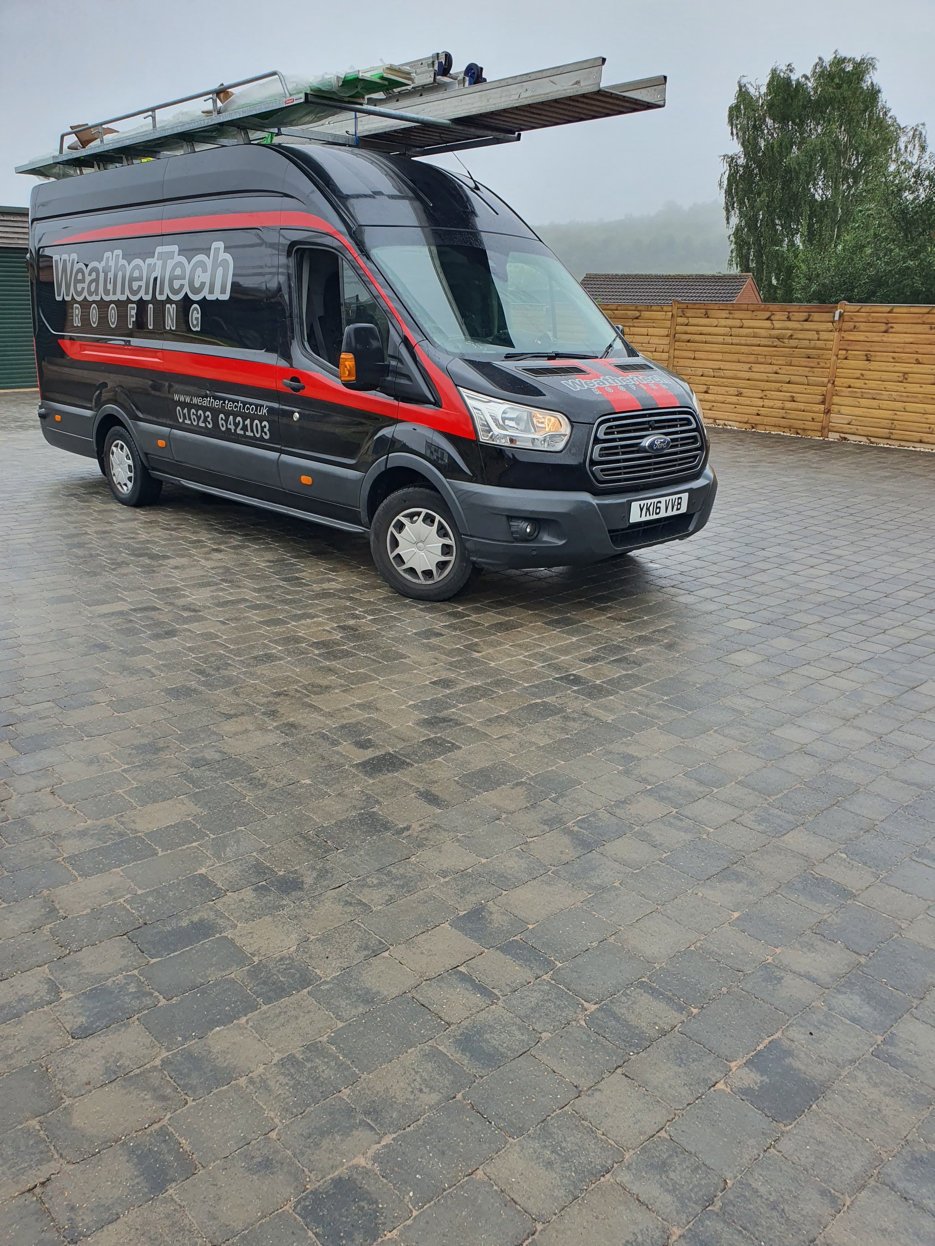WeatherTech Roofing company van with ladders on roof rack parked on block paving driveway