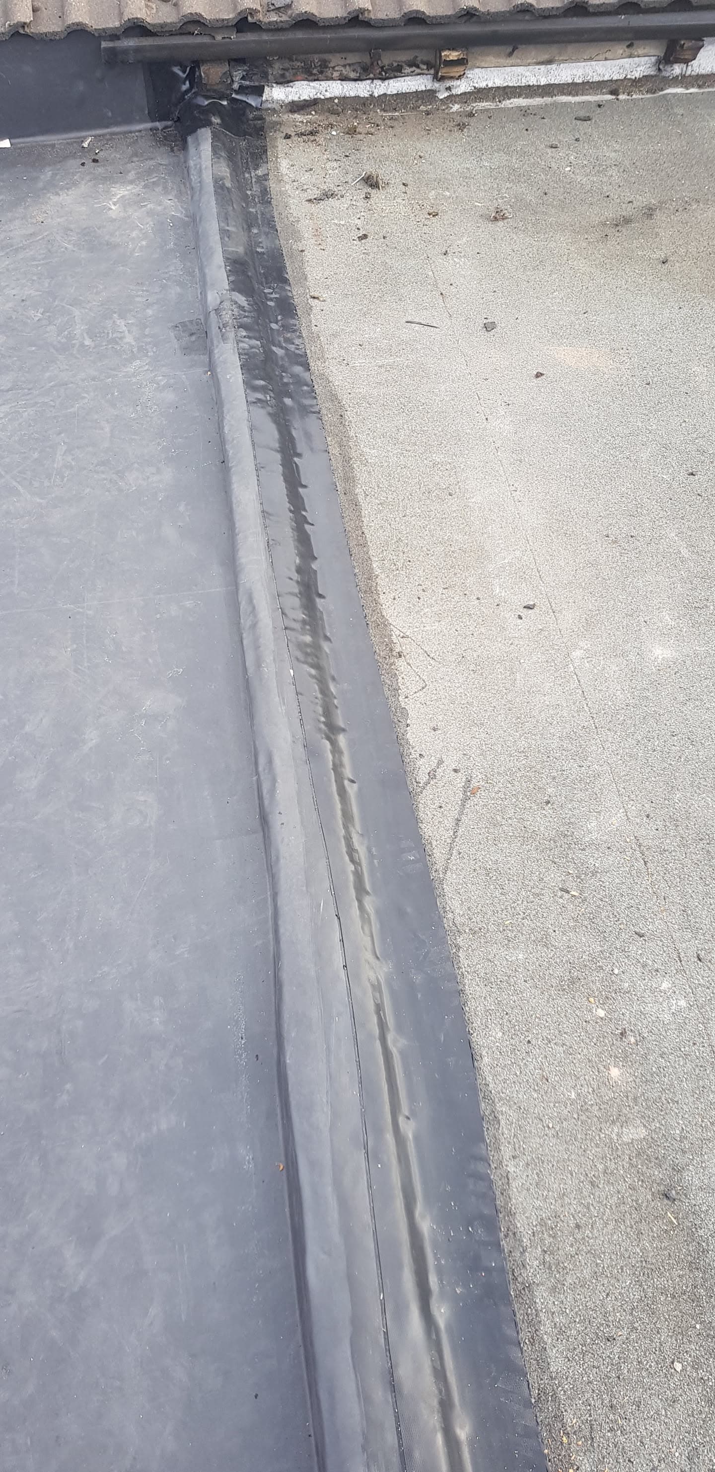 Flat roof with grey GRP fibreglass surface and lead flashing detail along edge