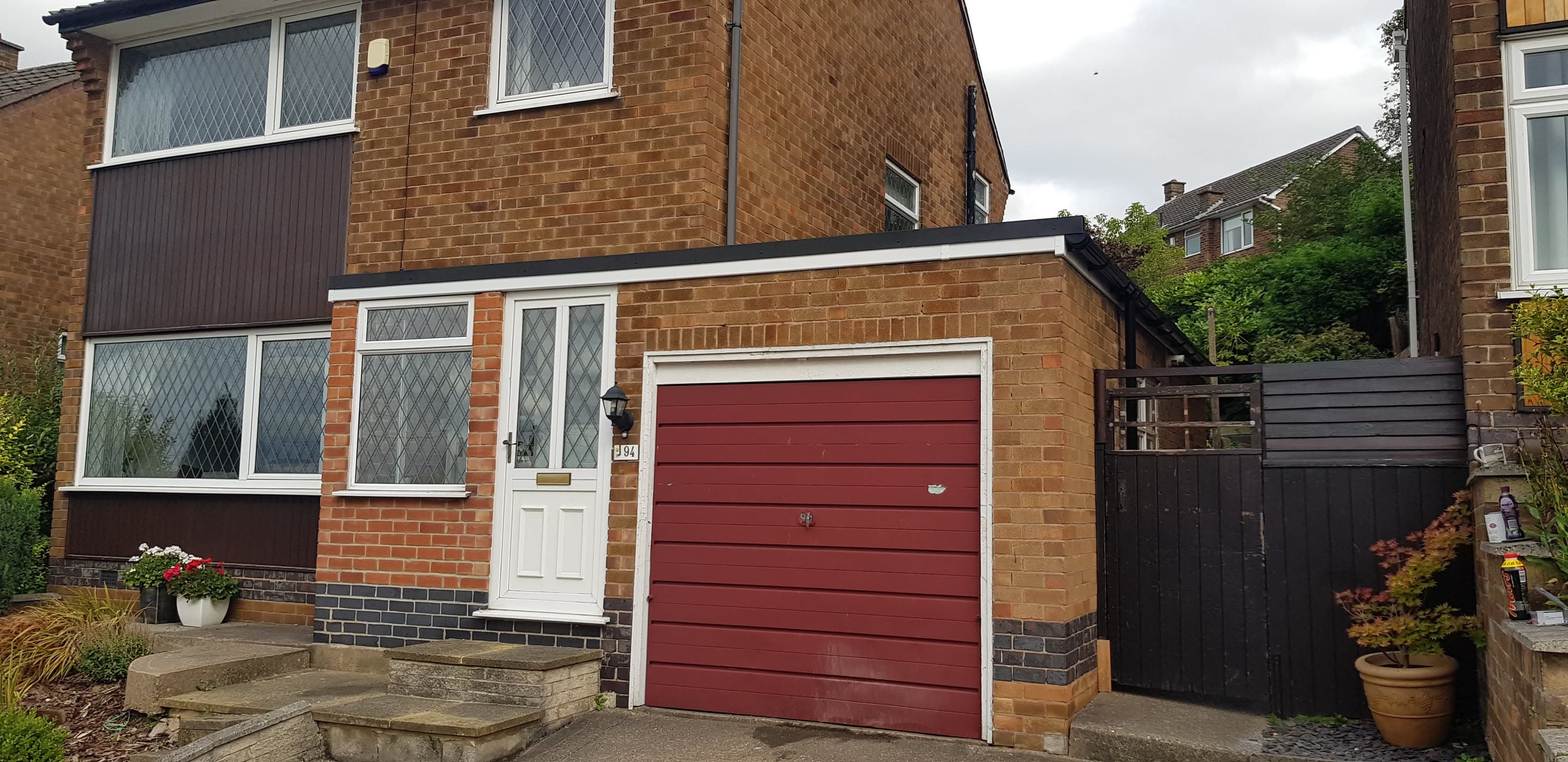 Flat roof extension on brick house with black fascias and guttering
