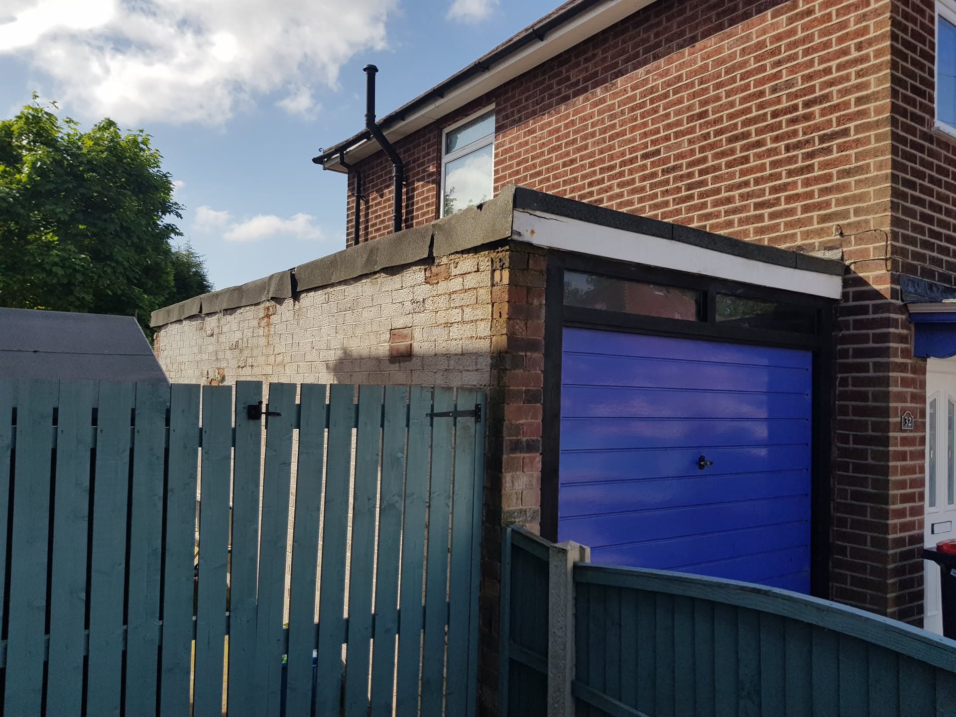 Flat roof with dark grey trim above garage on brick house