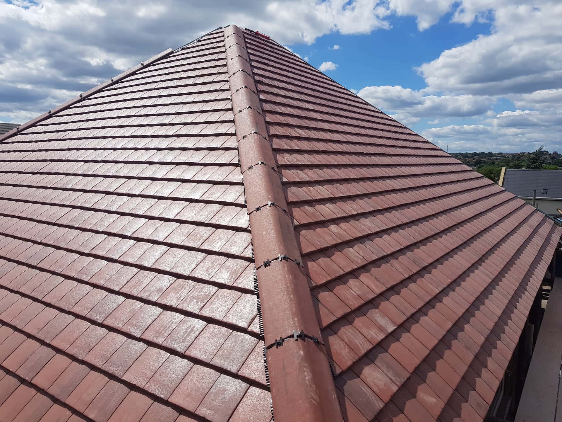 Newly completed pitched roof with terracotta concrete tiles and ridge capping
