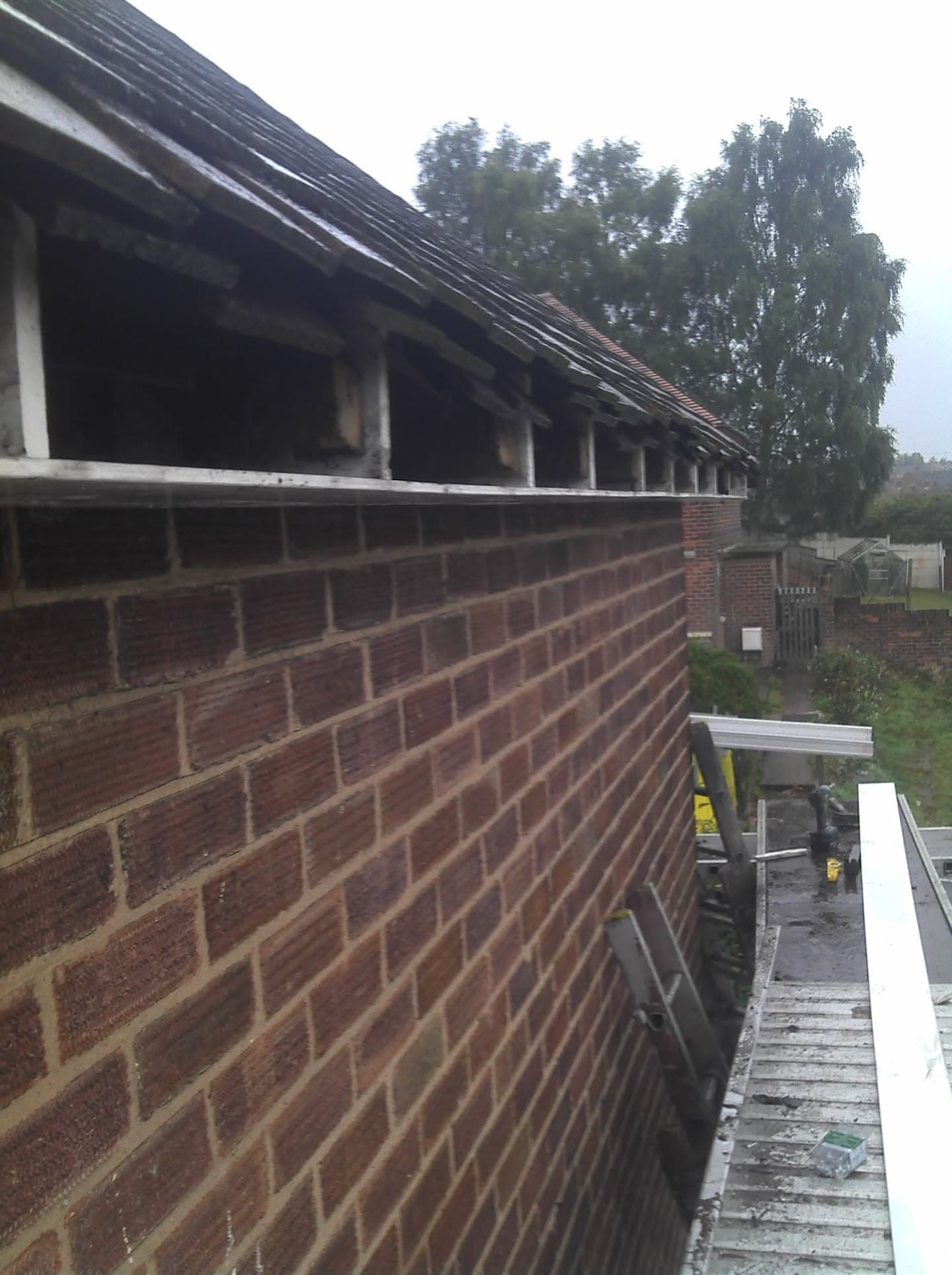 Pitched roof with dark tiles, white fascias and soffits on brick building