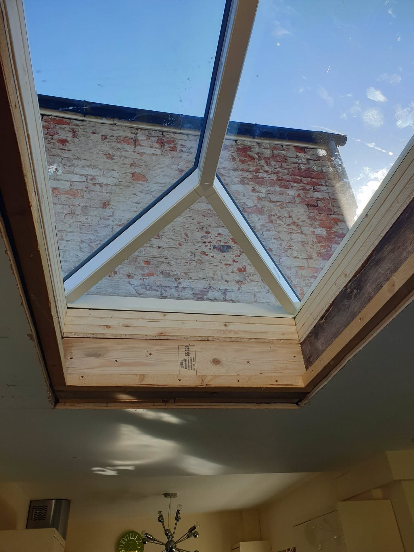 Glass roof lantern with timber frame viewed from inside, showing exposed brick wall