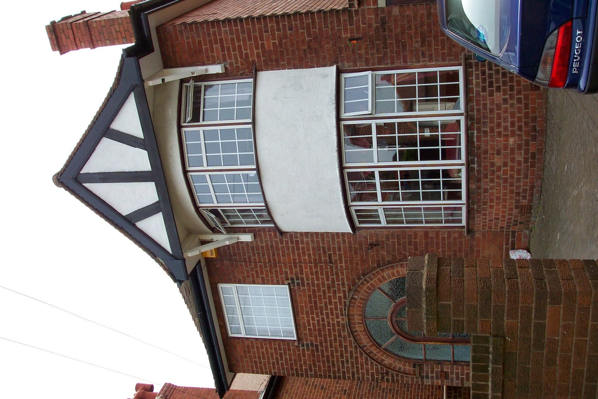 Red clay tiled pitched roof with dark fascias and soffits on brick house