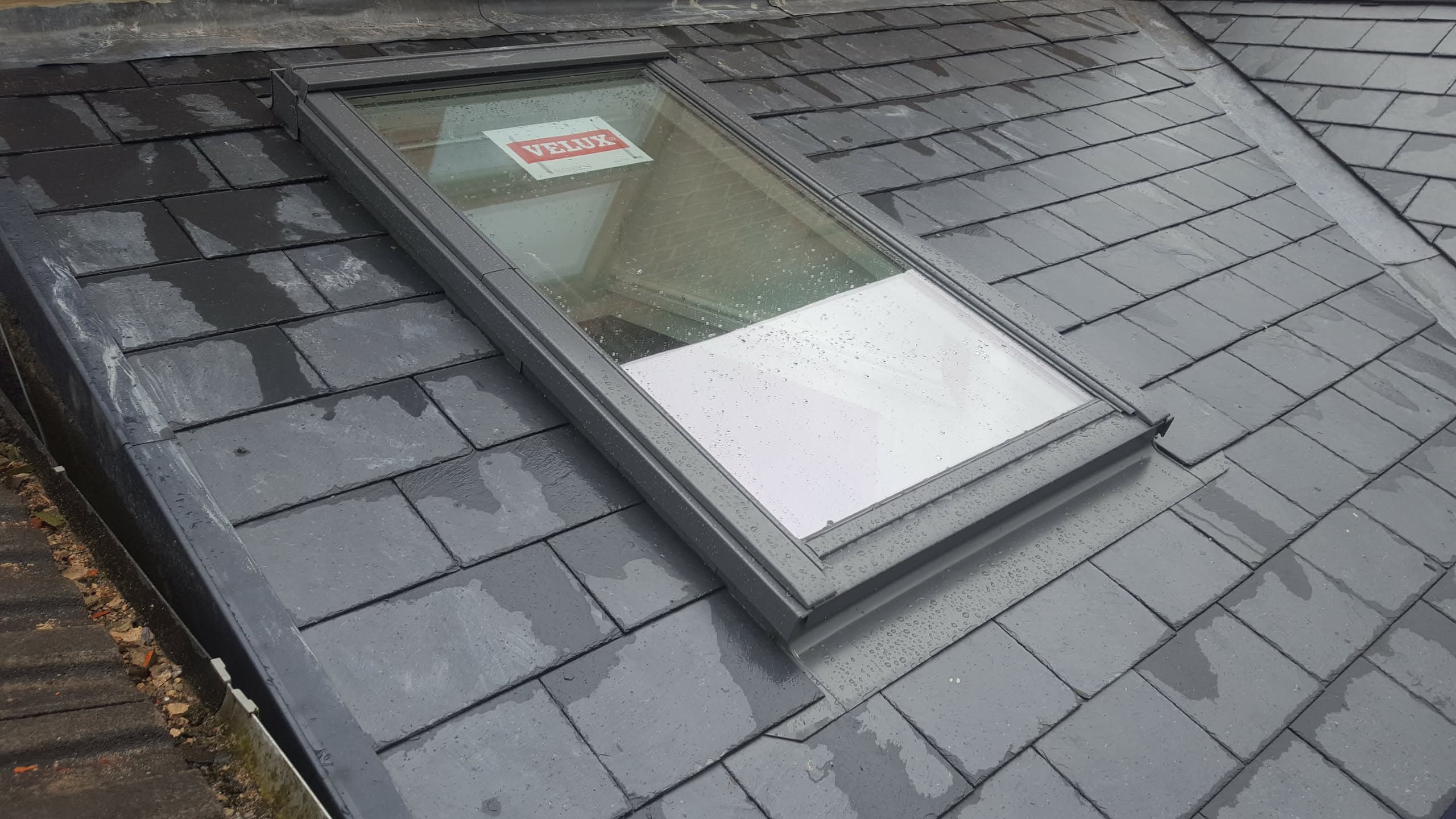 Grey slate pitched roof with Velux roof window and lead flashing