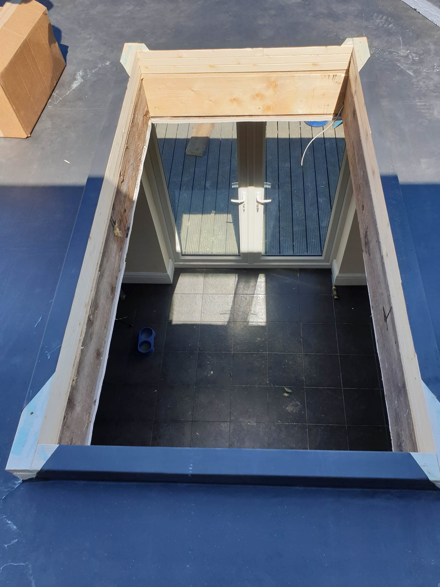 Flat roof with blue GRP fibreglass finish and timber-framed roof light opening