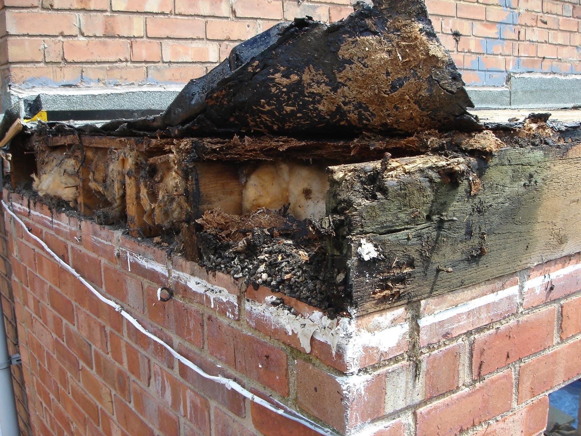 Severely damaged chimney stack with burnt and deteriorated brickwork and flashing