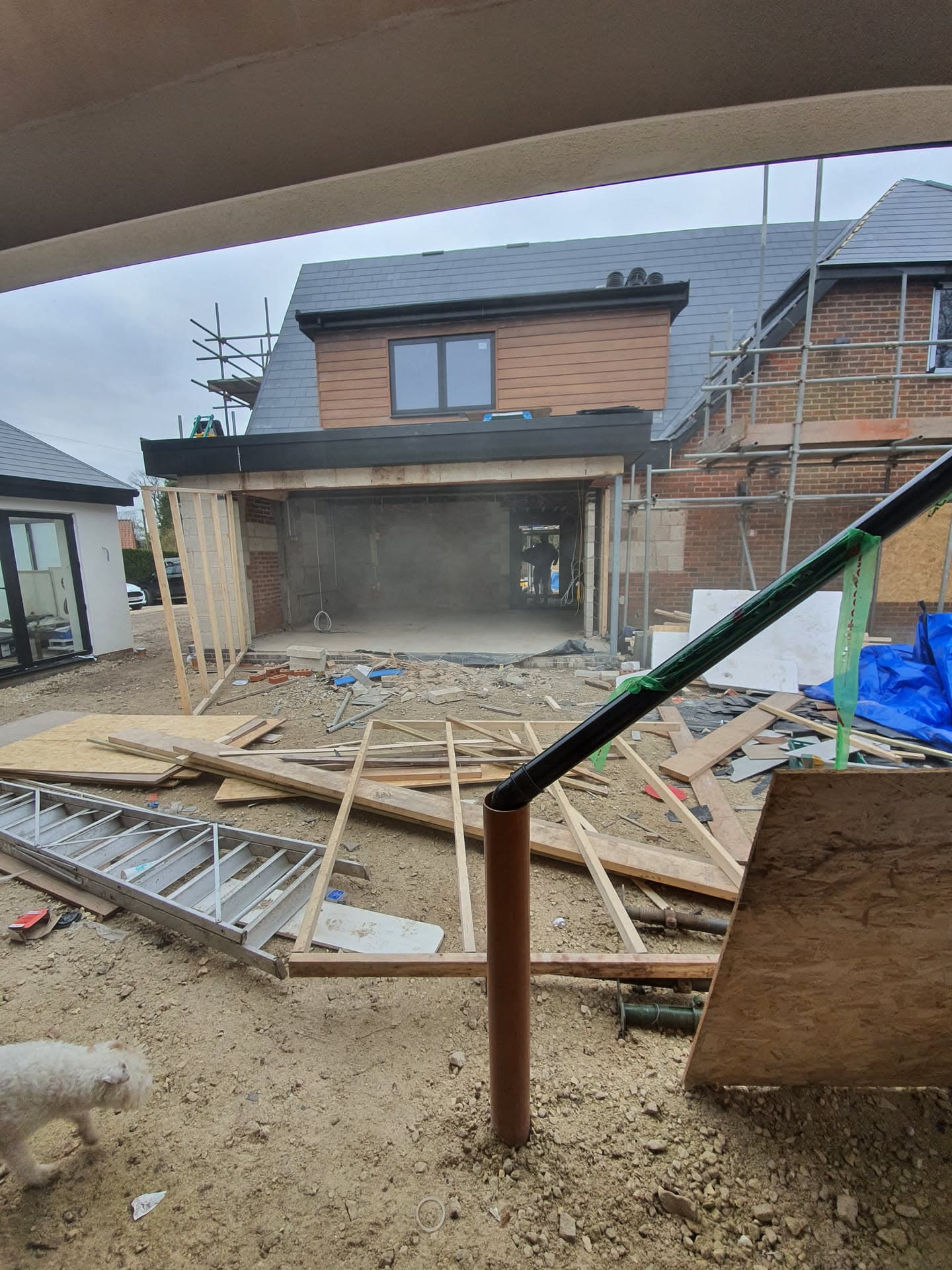 Residential extension with grey slate pitched roof and timber cladding under construction