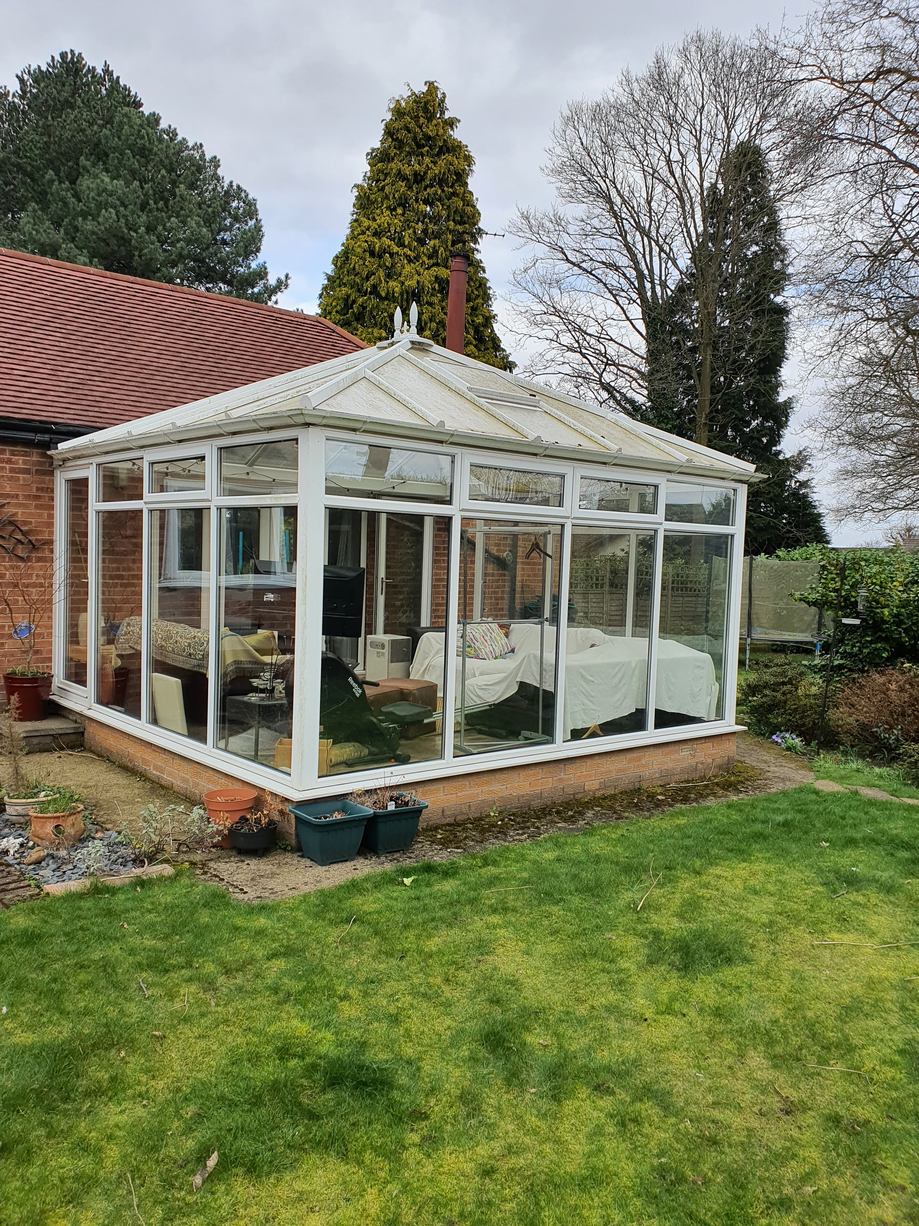 White uPVC conservatory with pitched glass roof attached to brick house with tiled roof
