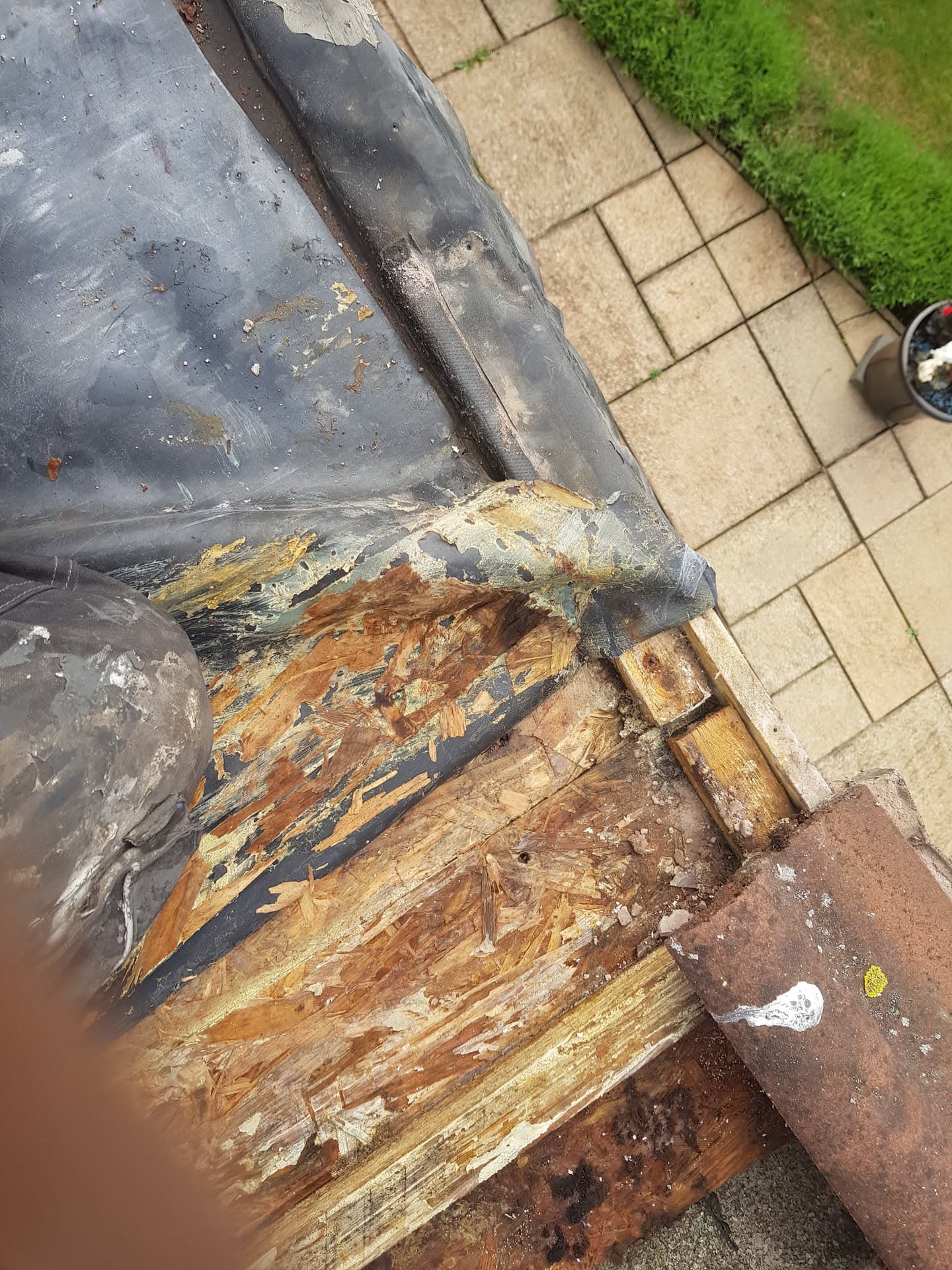 Rotten fascia board with severe water damage requiring replacement on flat roof edge
