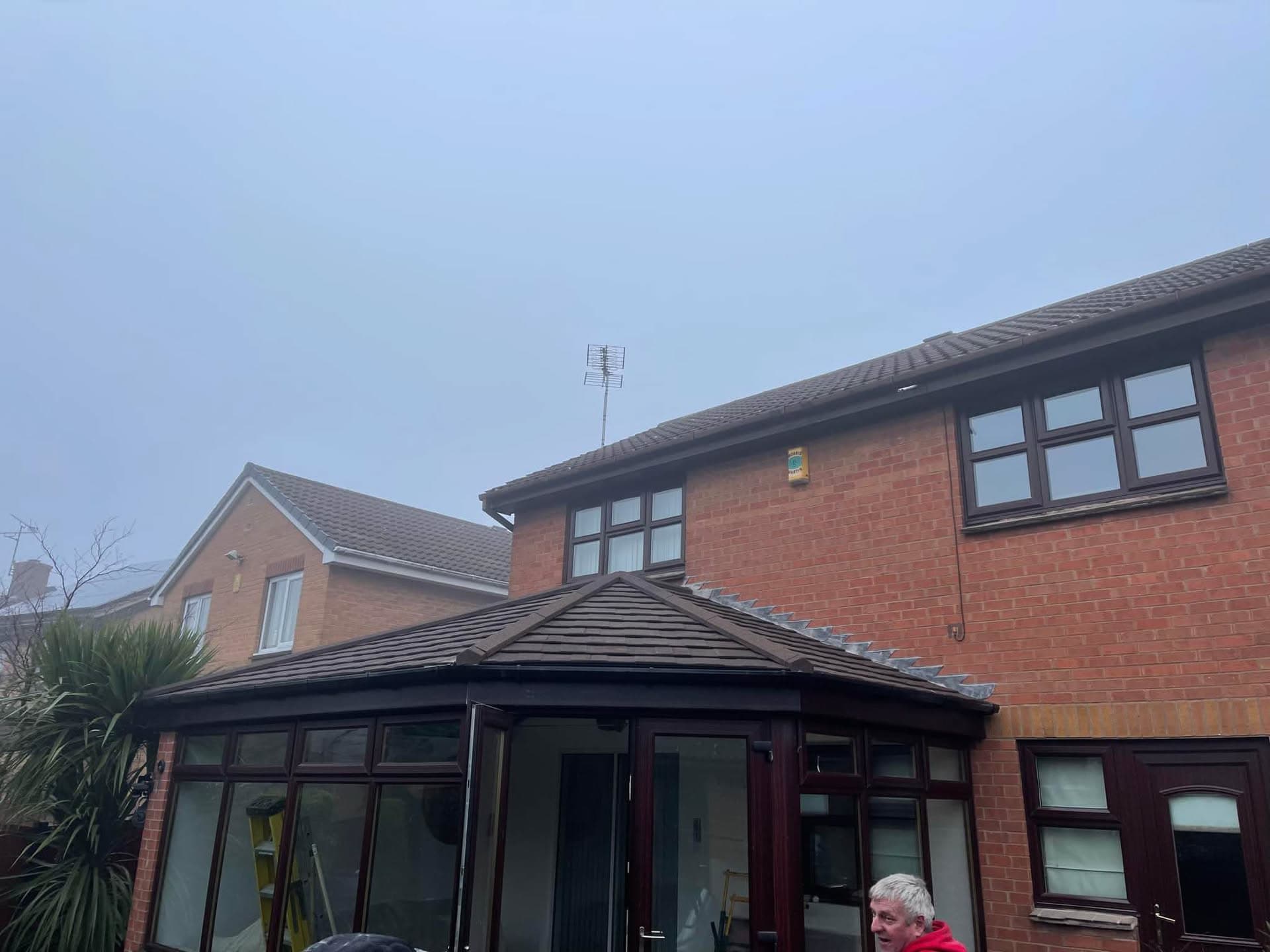 Tiled conservatory roof with dark tiles and fascias on red brick house