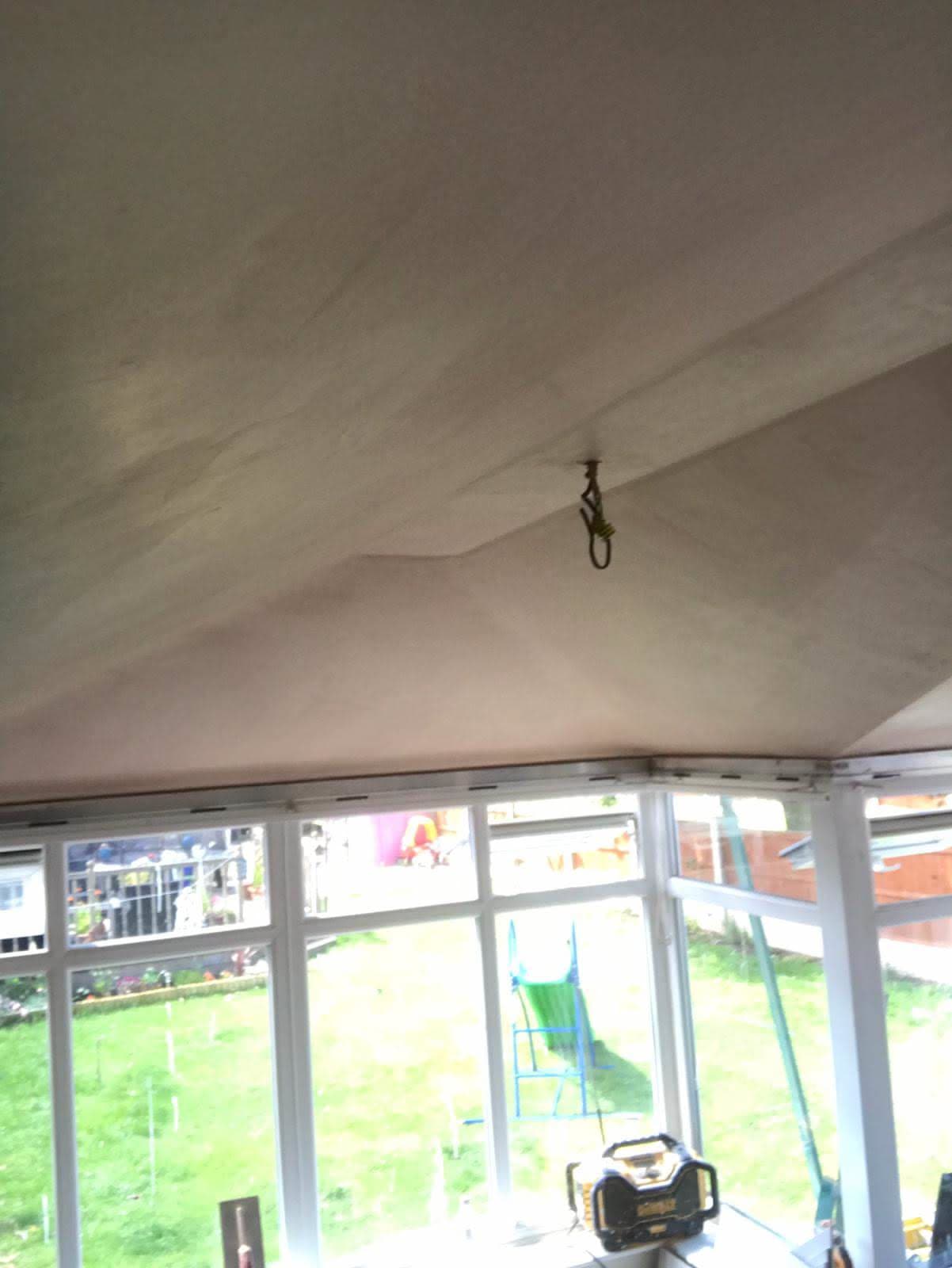 White plastered conservatory ceiling with light fixture hook visible