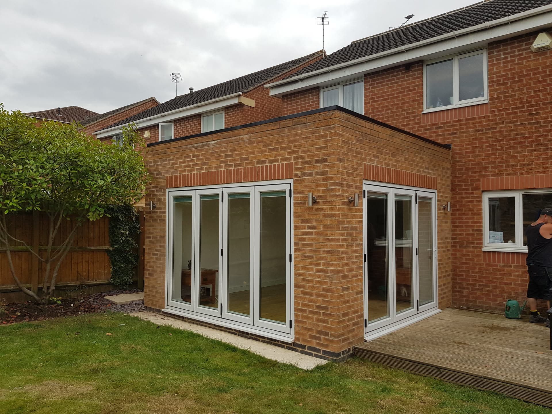 Flat roof extension on brick house with white bifold doors and decking