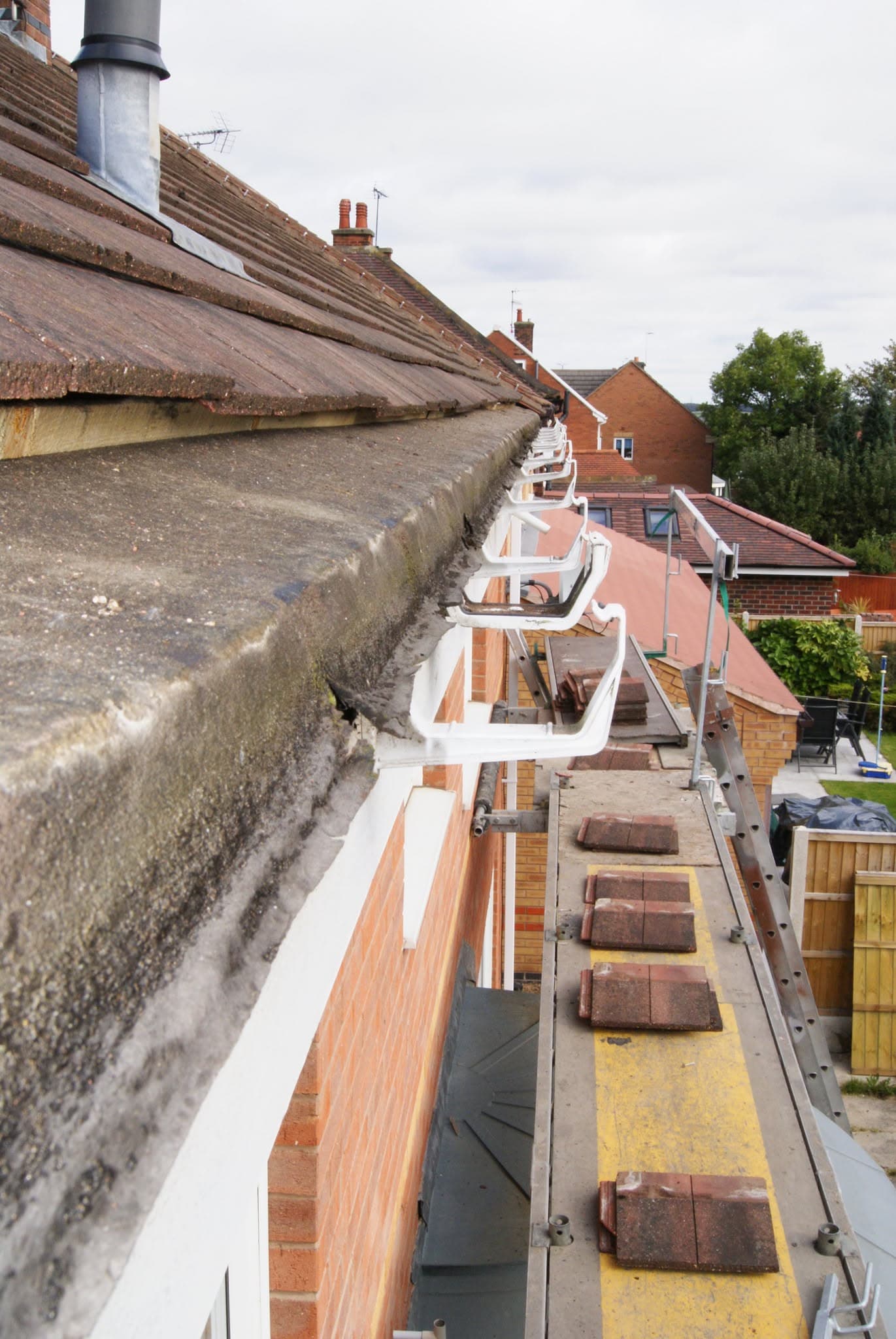Pitched tiled roof with white fascias and guttering installation in progress