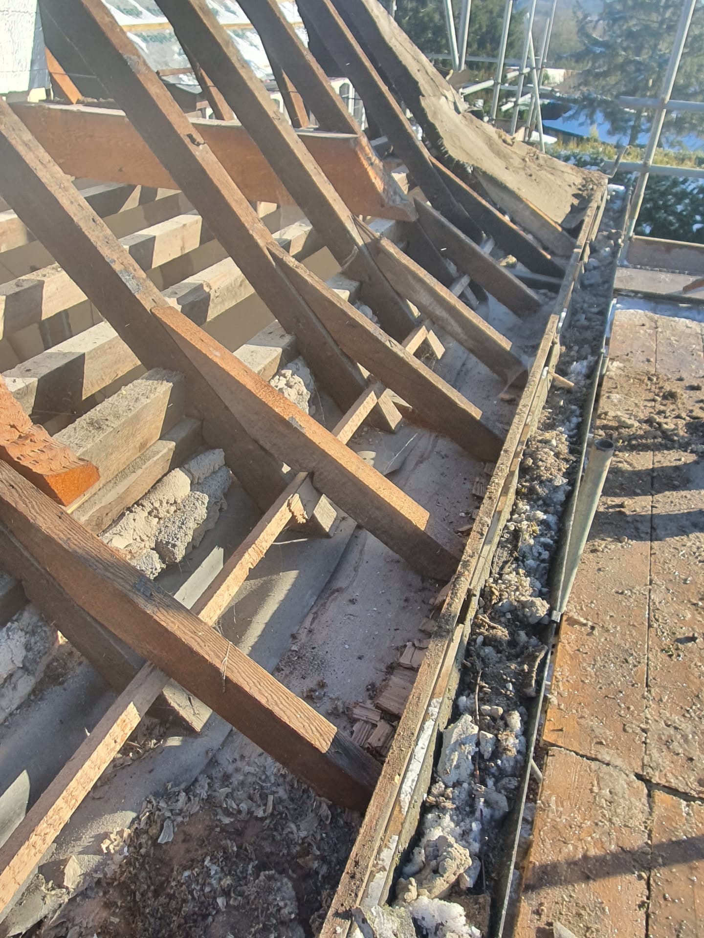 Pitched roof stripped back to timber rafters and battens during re-roofing work with scaffolding visible