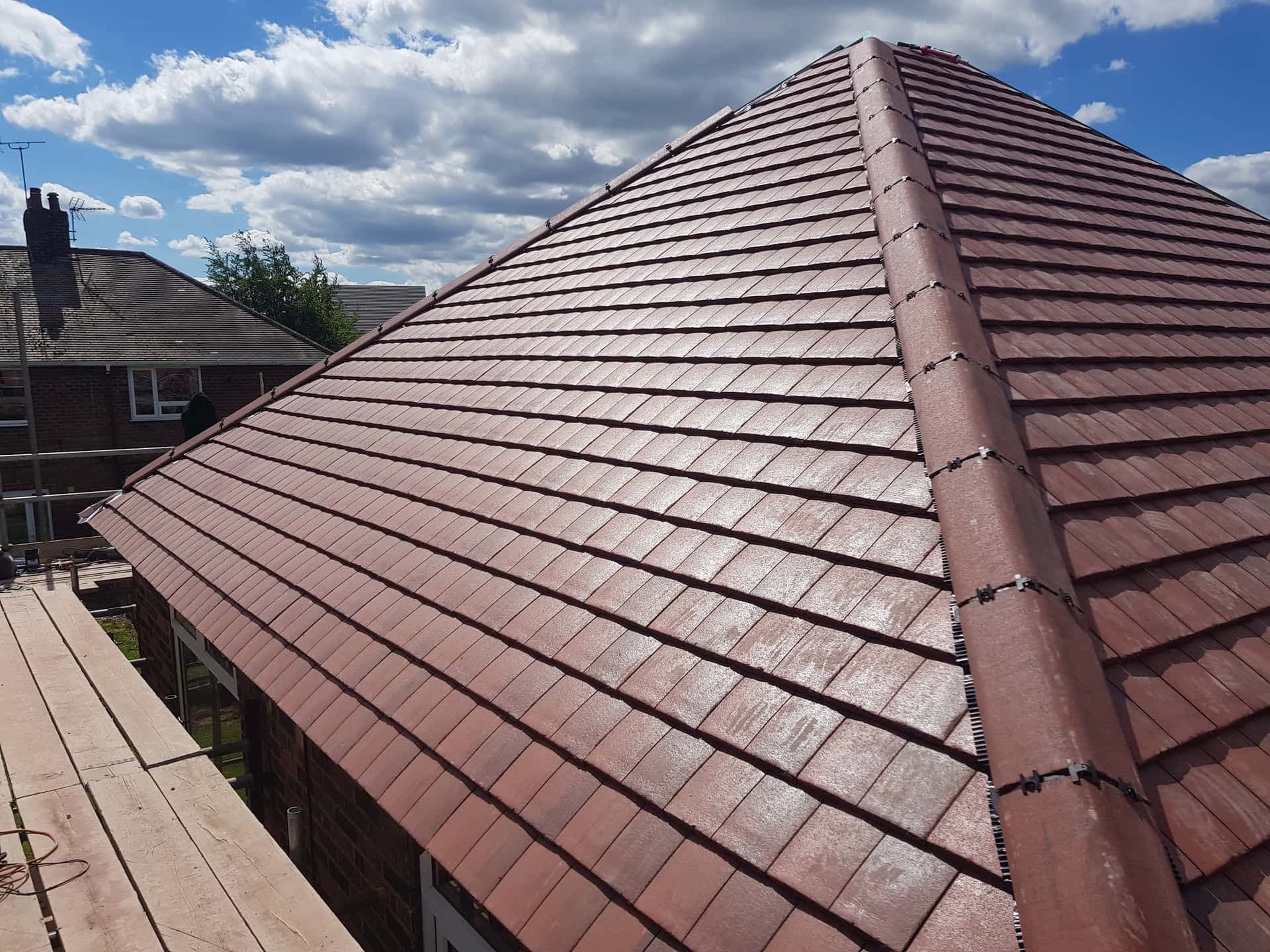 Newly completed pitched roof with brown concrete tiles and ridge tiles