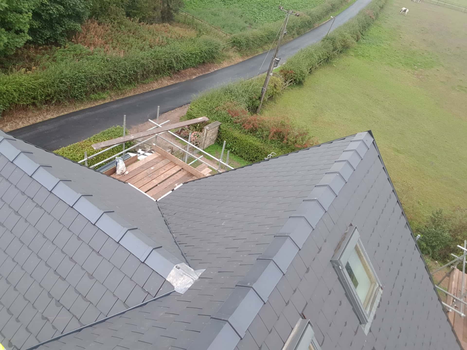 Newly completed grey slate pitched roof with ridge tiles and dormer window