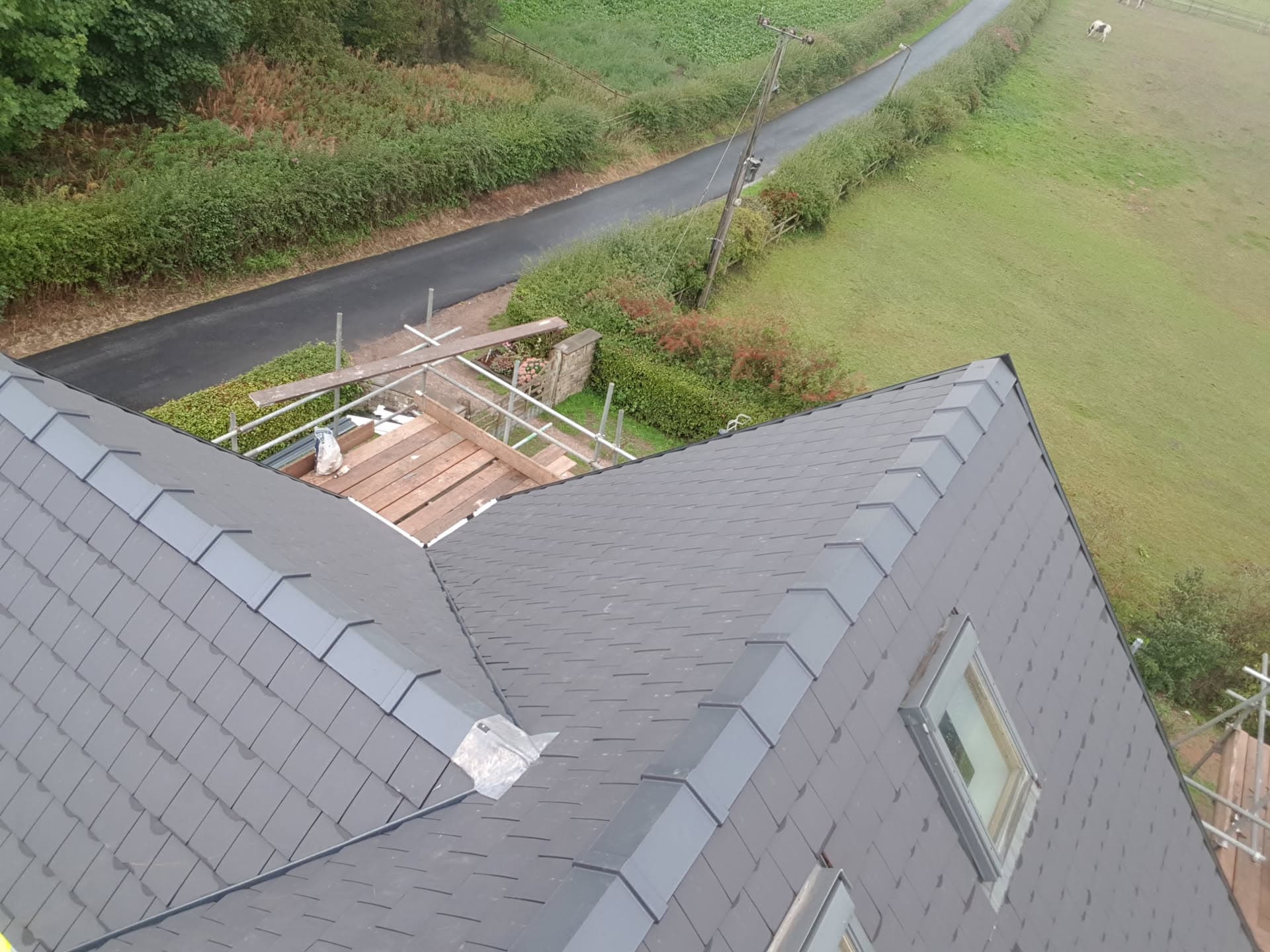 Newly completed grey slate pitched roof with ridge tiles and dormer window