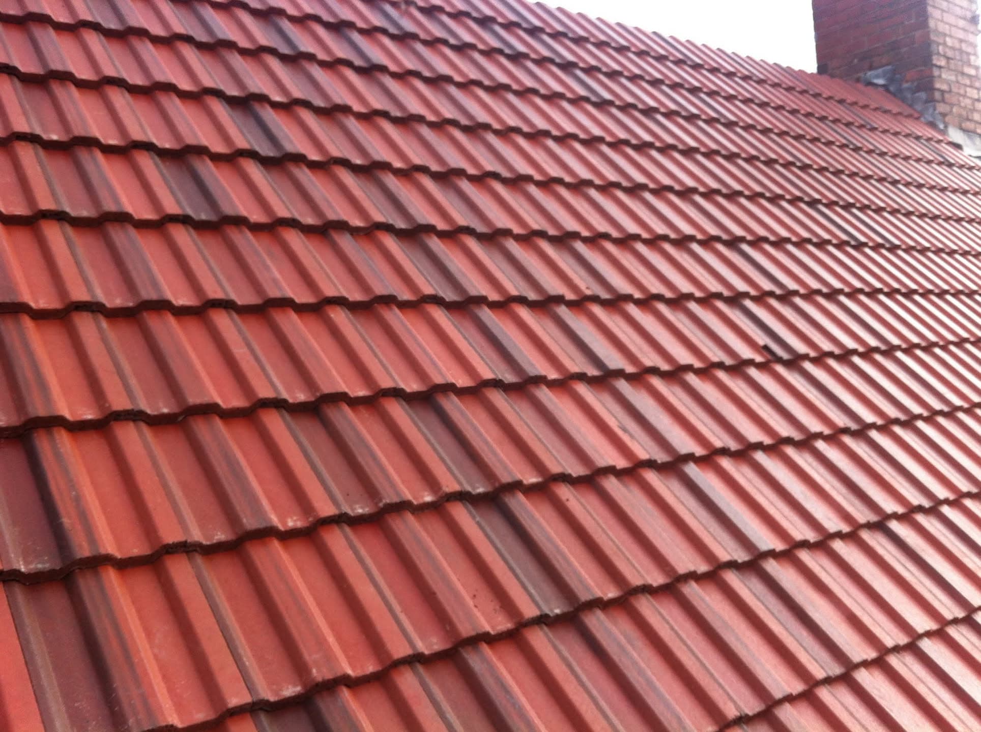 Pitched roof with red concrete tiles and brick chimney stack