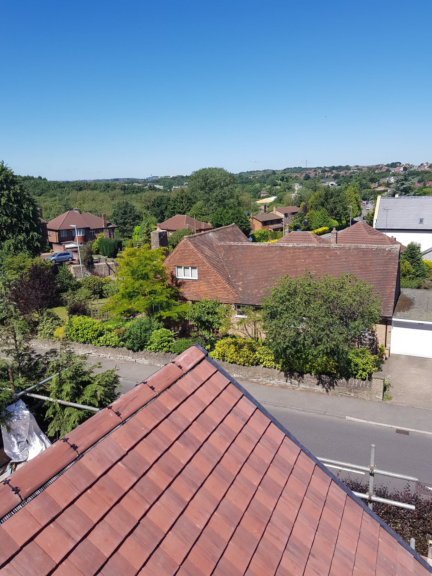 Pitched roof with red concrete tiles and dry ridge system overlooking residential area
