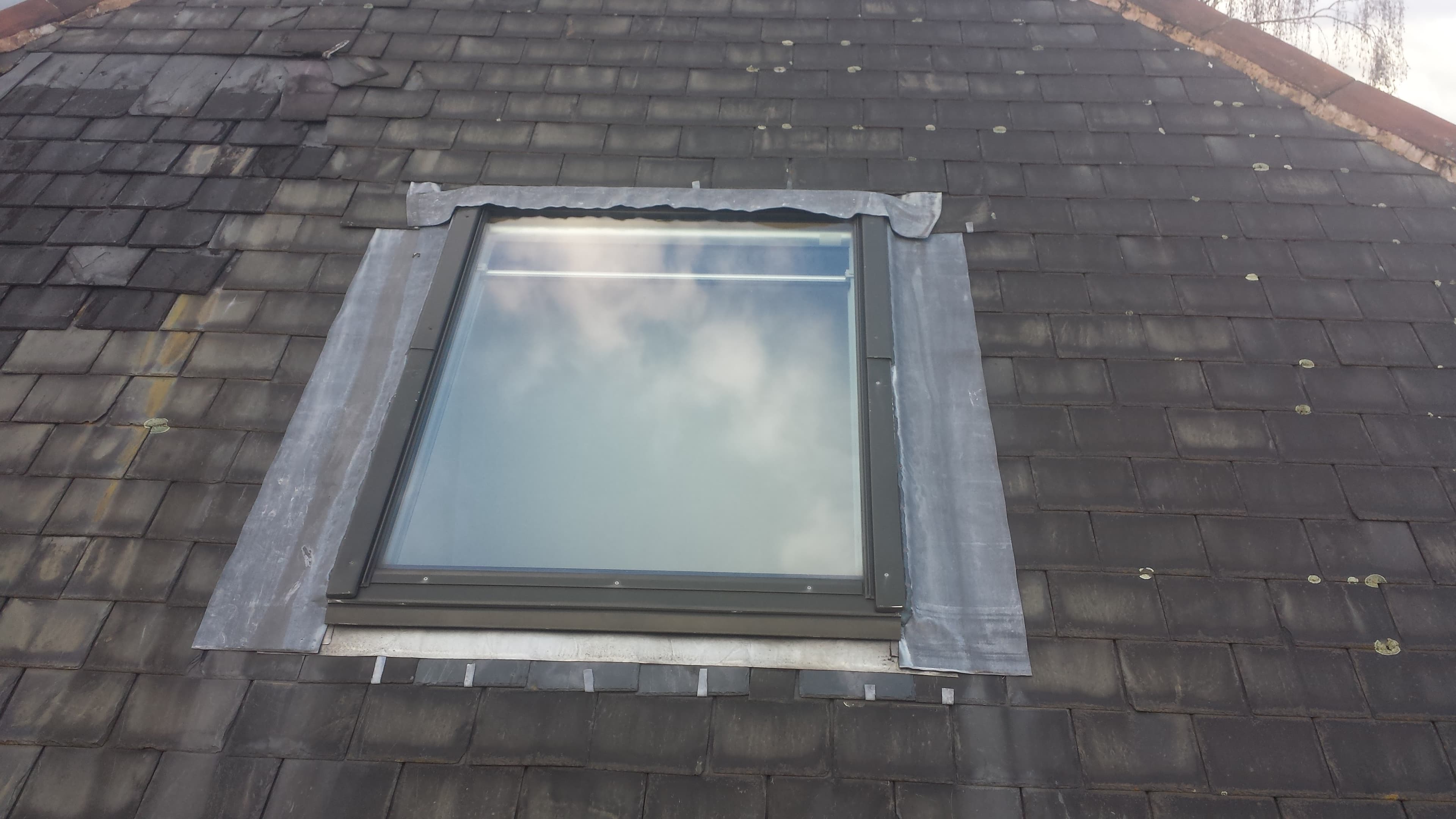 Velux roof window with lead flashing installed on dark slate pitched roof