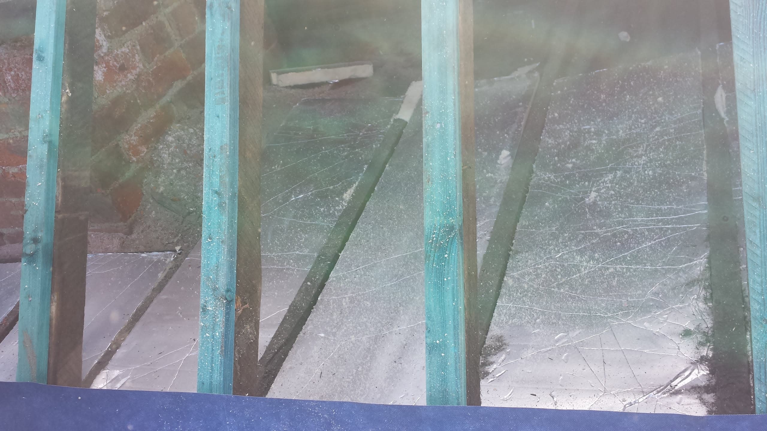 Glass conservatory roof panels with turquoise glazing bars viewed from above