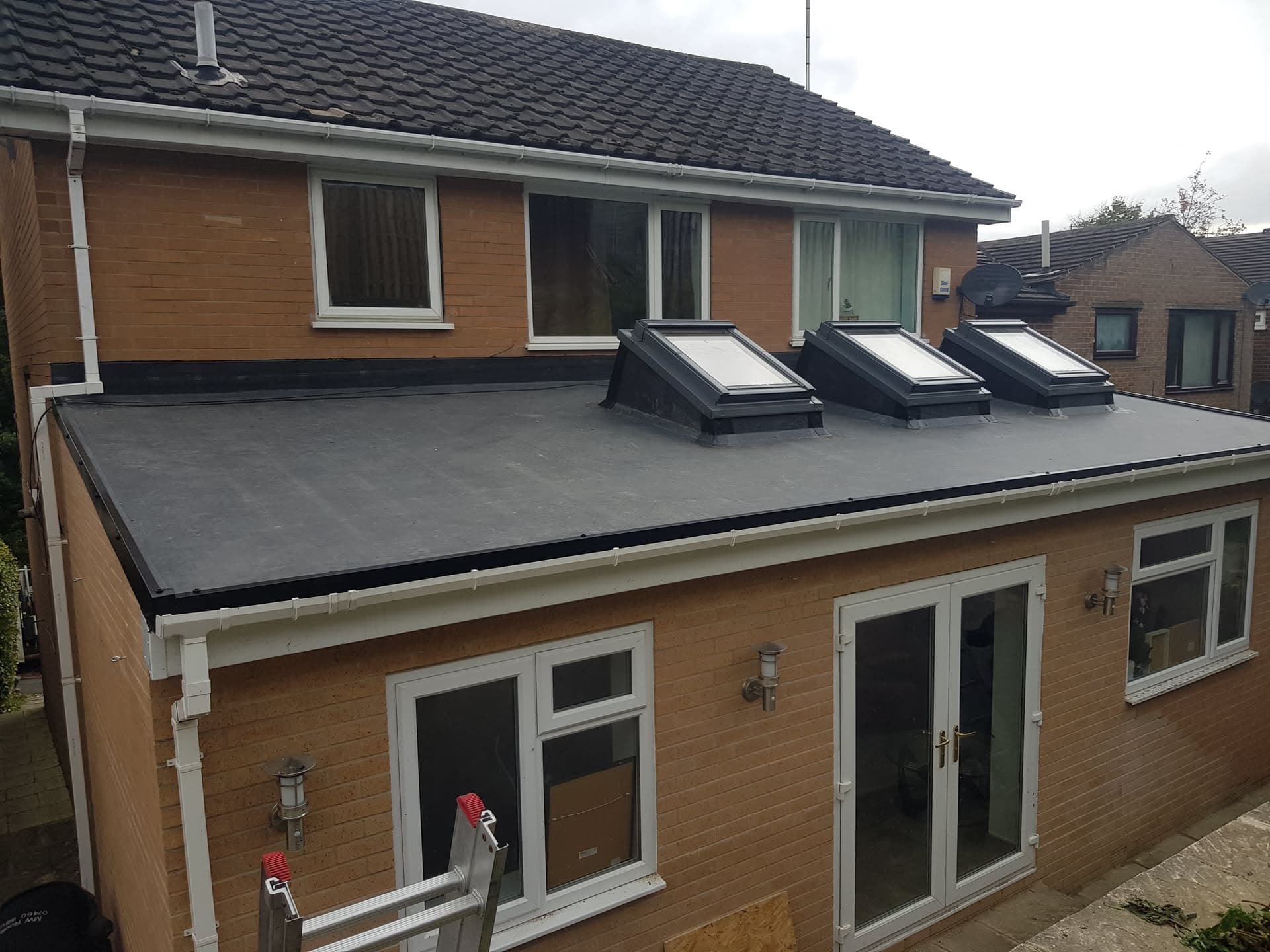 Single-storey extension with grey flat roof and three black-framed roof windows